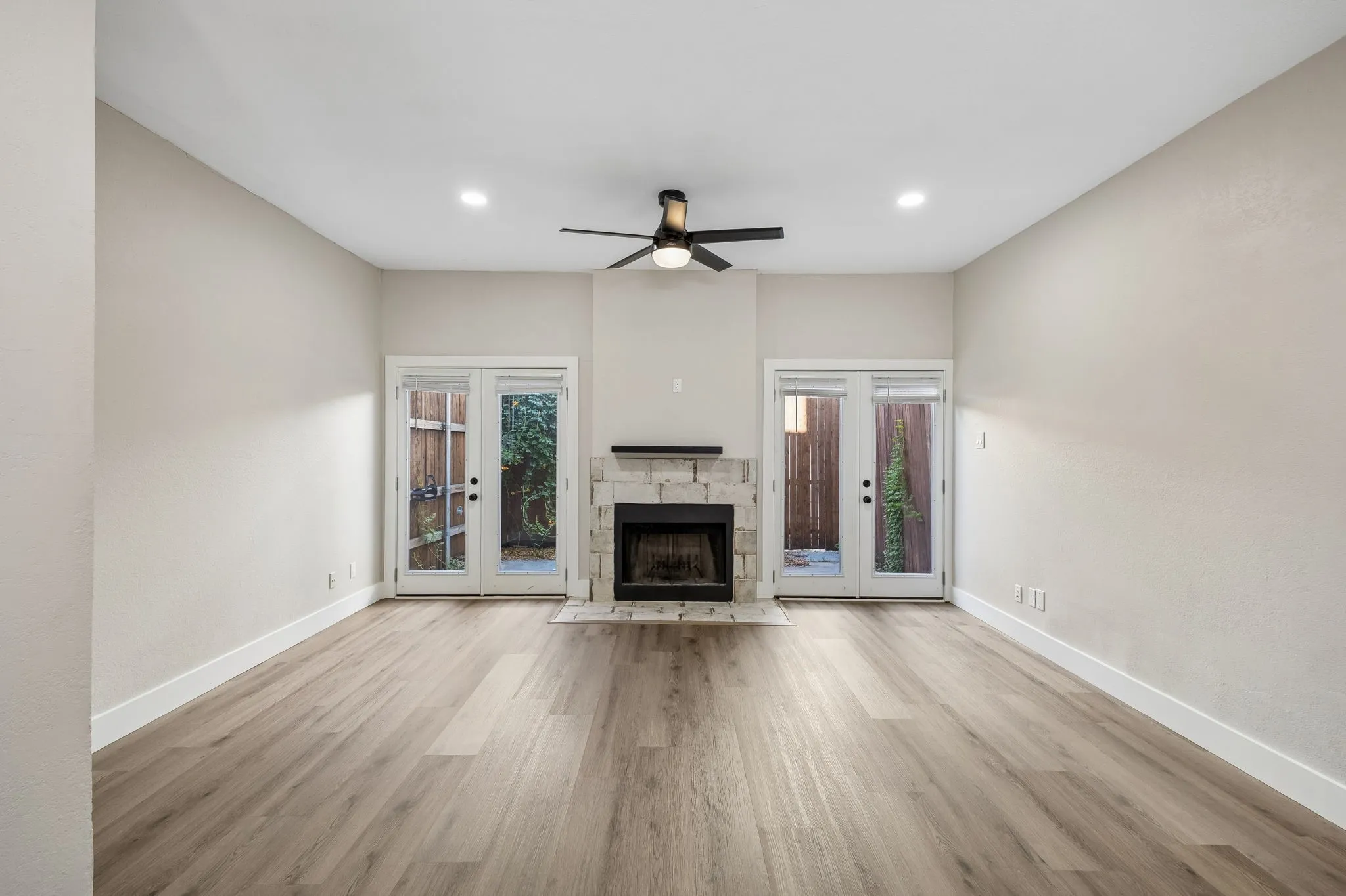 Spacious room featuring wood-finish flooring, a stone-surround fireplace, and recessed lighting