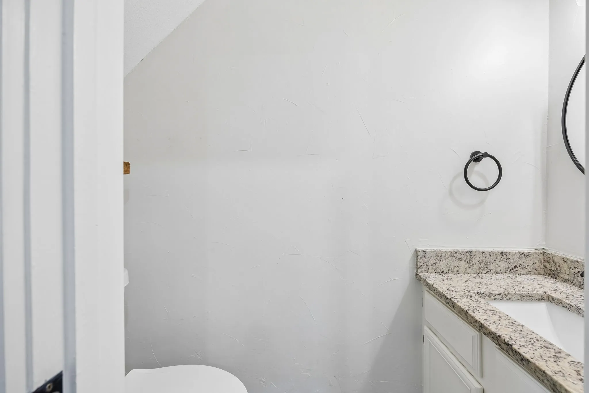 Vanity with a speckled stone countertop, an integrated sink, and white cabinetry