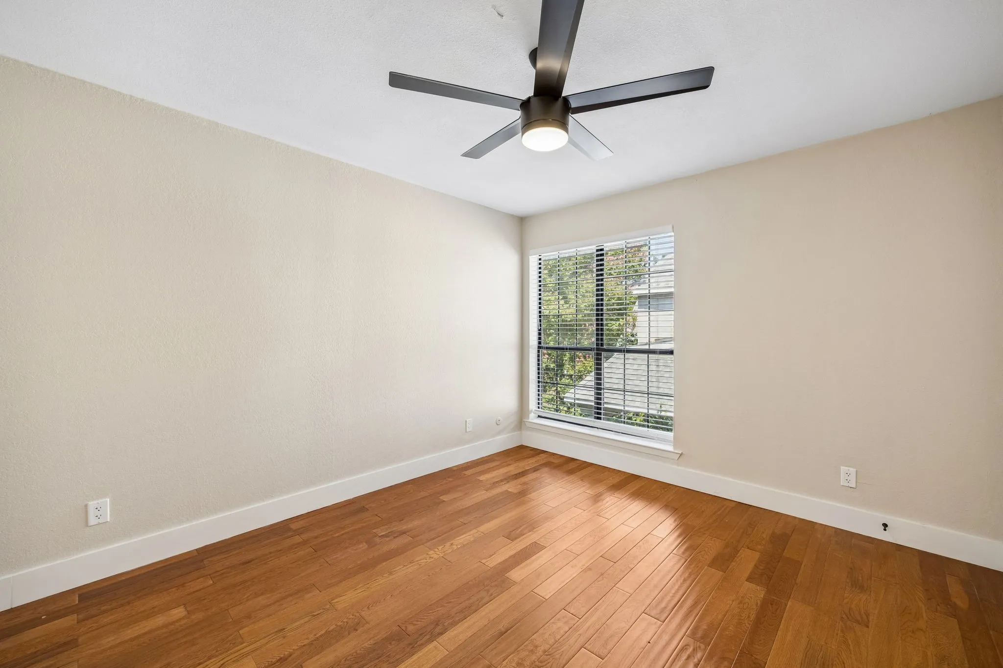 Room with wood-finish flooring, a window with blinds, and a ceiling fan