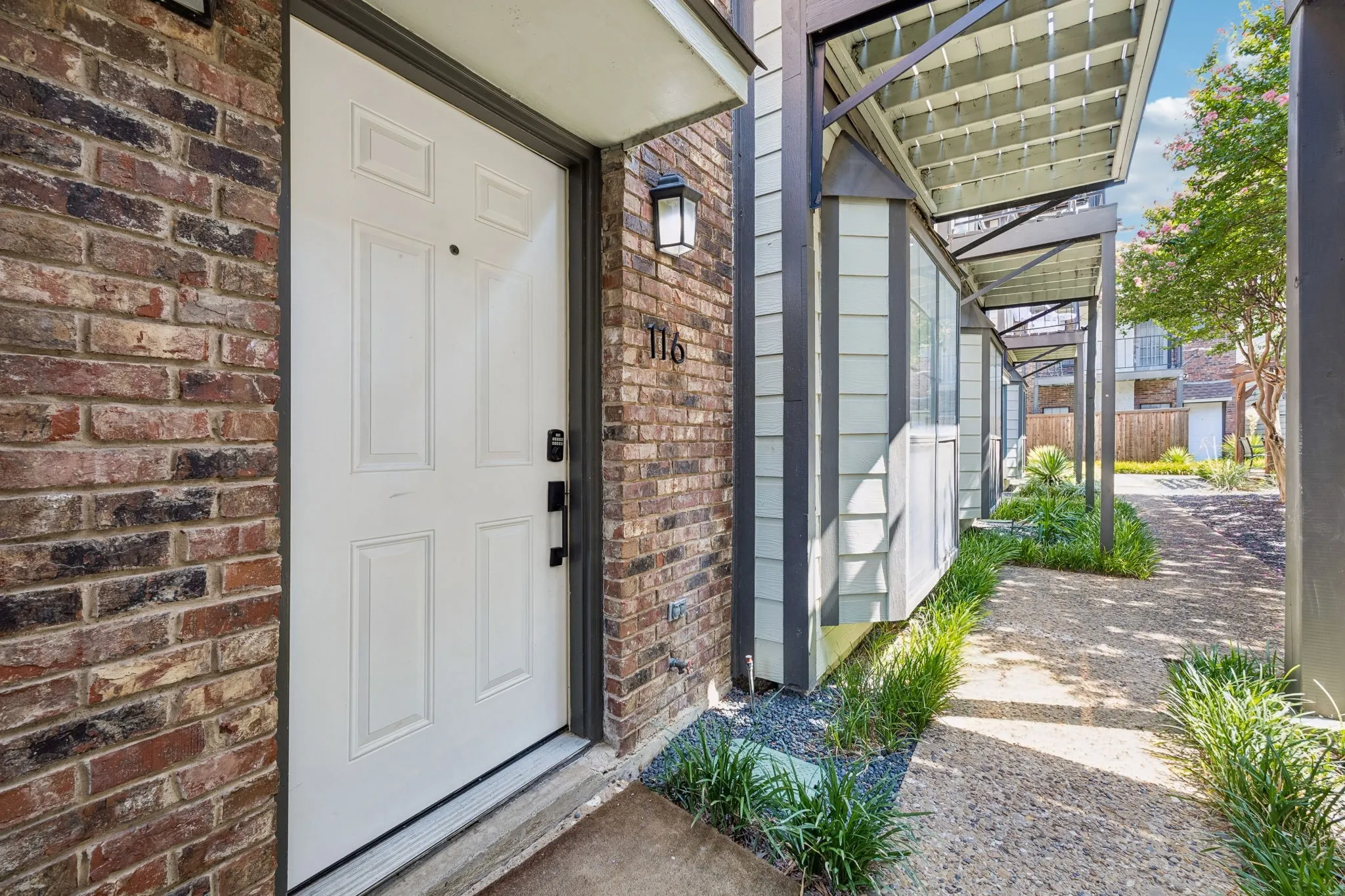 Brick facade entryway featuring a paneled white door with matte black hardware