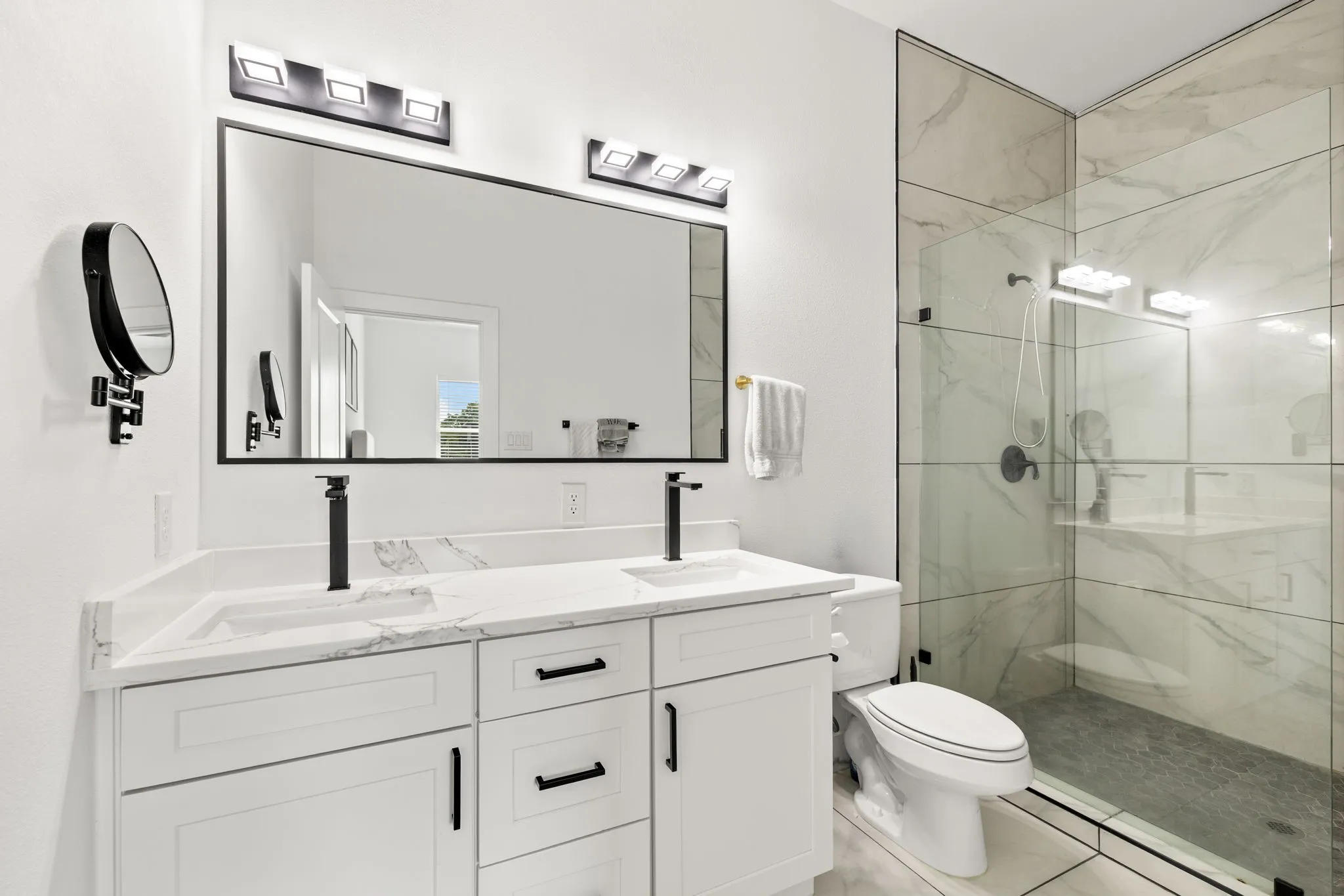 Bathroom featuring a dual vanity with white cabinetry, white countertops, and matte black fixtures