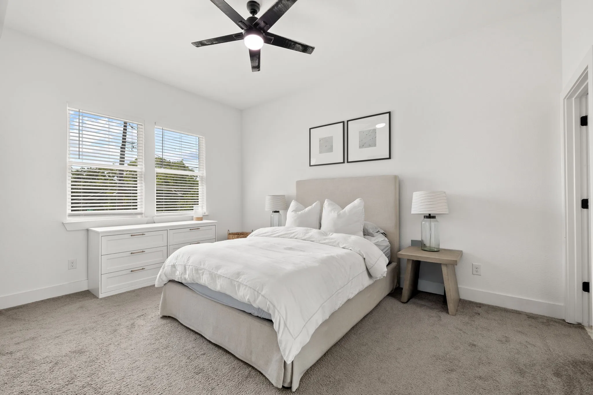 Spacious room featuring neutral carpeting, a modern ceiling fan, and white walls