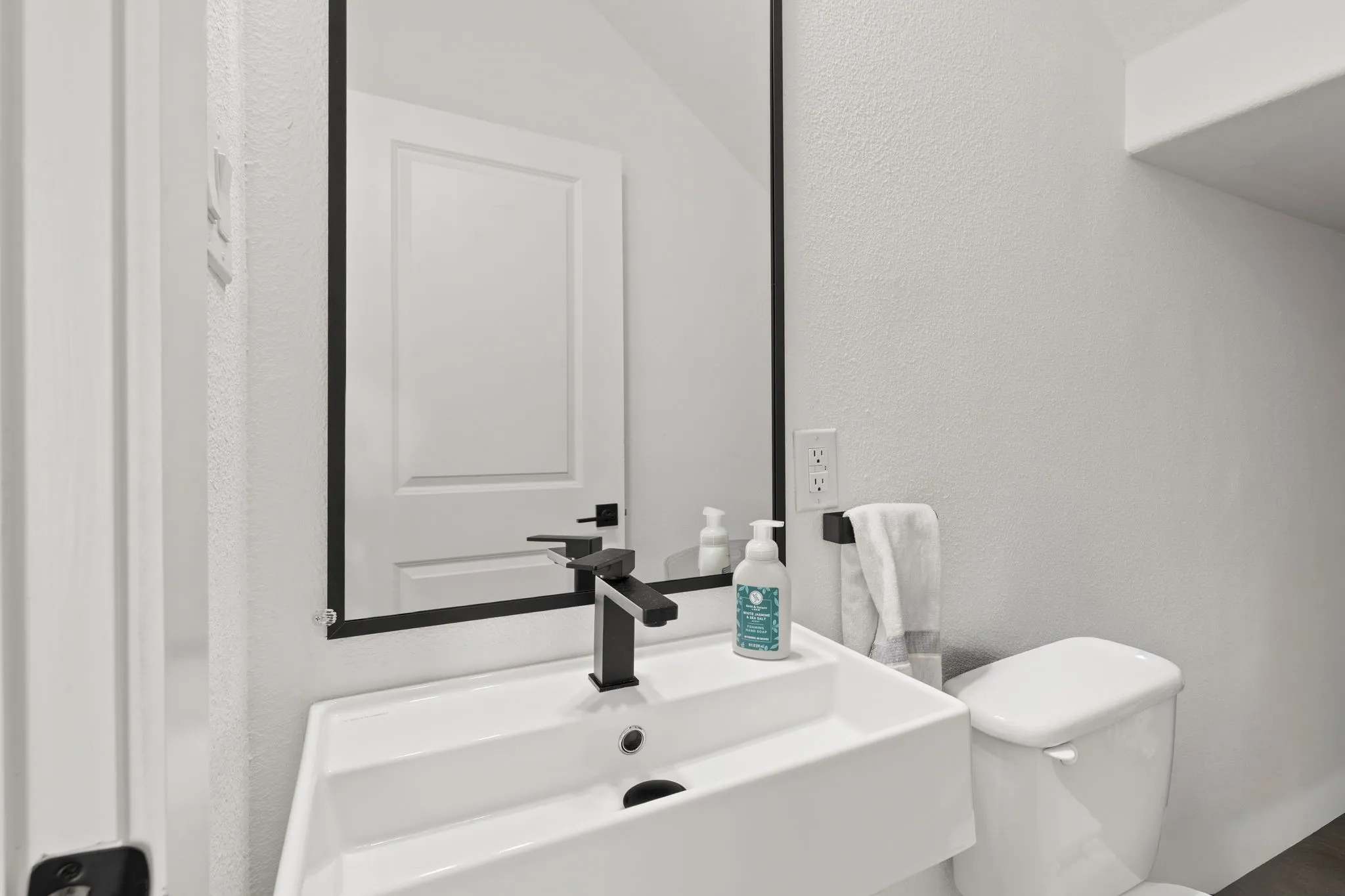 Modern bathroom featuring a rectangular vessel sink with a quartz countertop, matte black wall-mounted faucet, and polished chrome fixtures