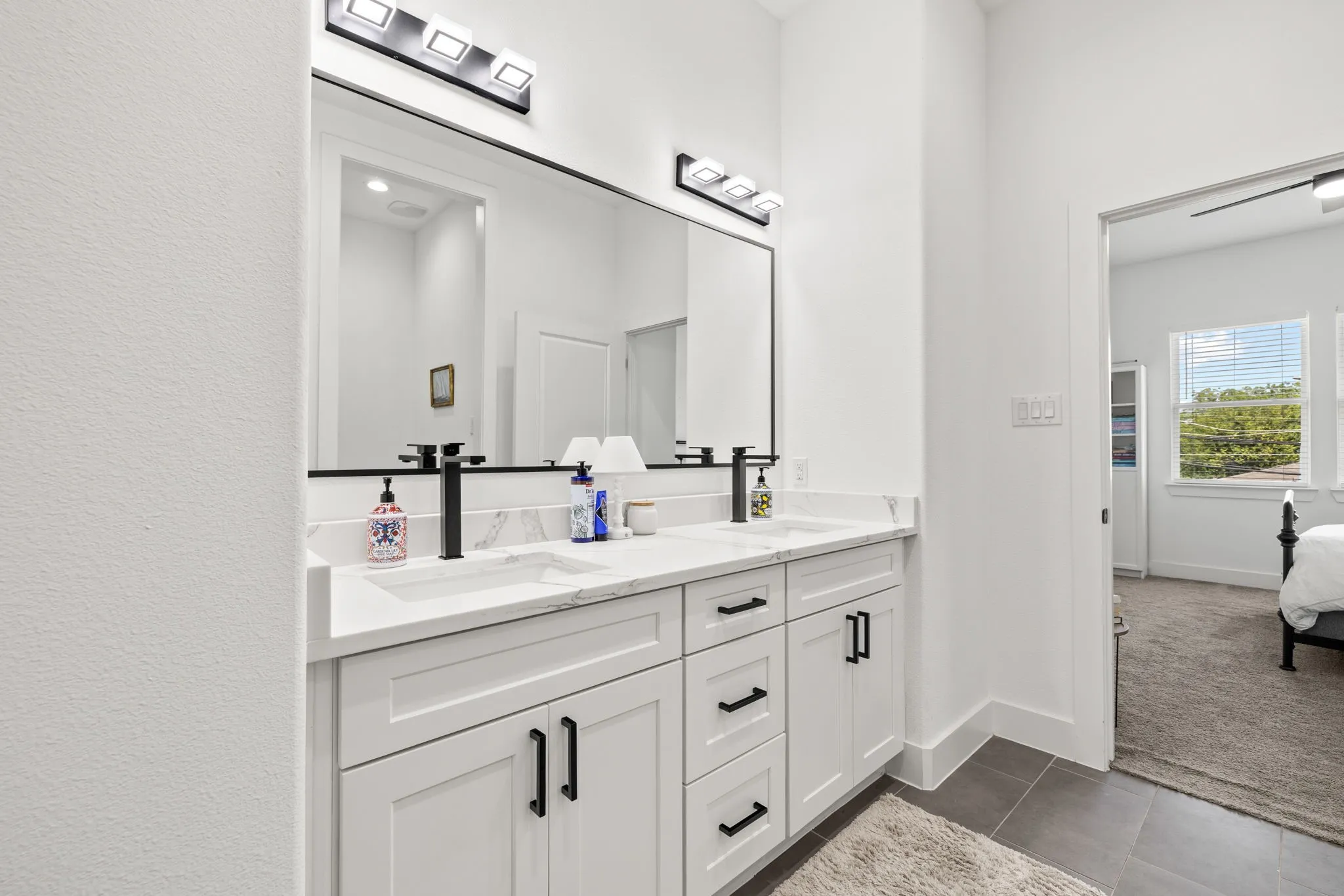 Double vanity featuring white shaker cabinetry, quartz countertops, undermount sinks, and matte black fixtures