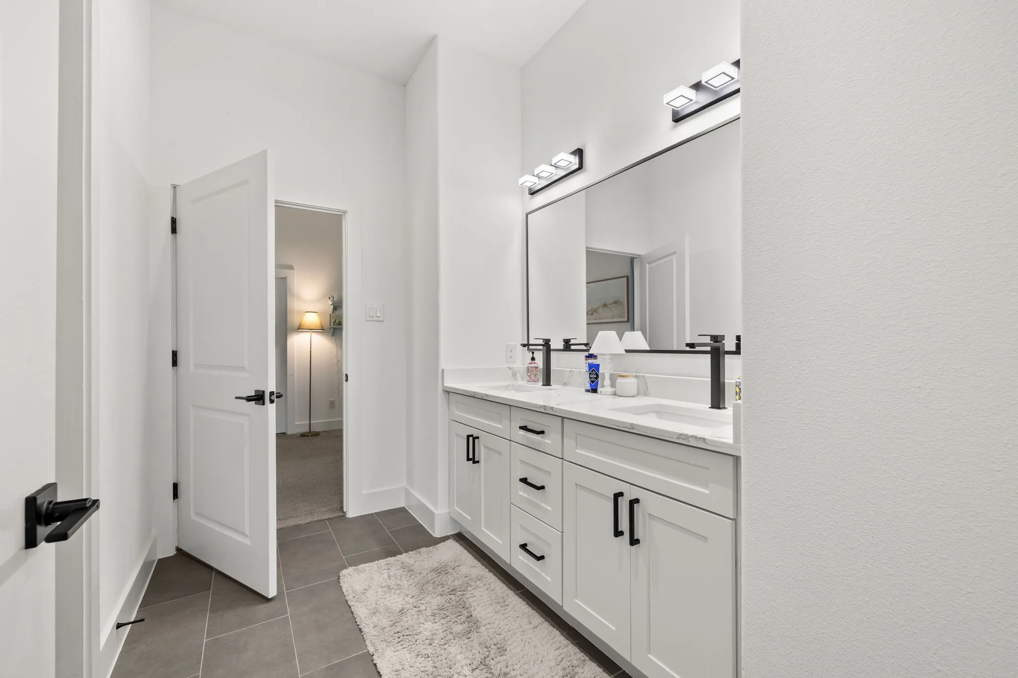 Bathroom featuring a double vanity with white cabinetry, white countertops, and matte black hardware