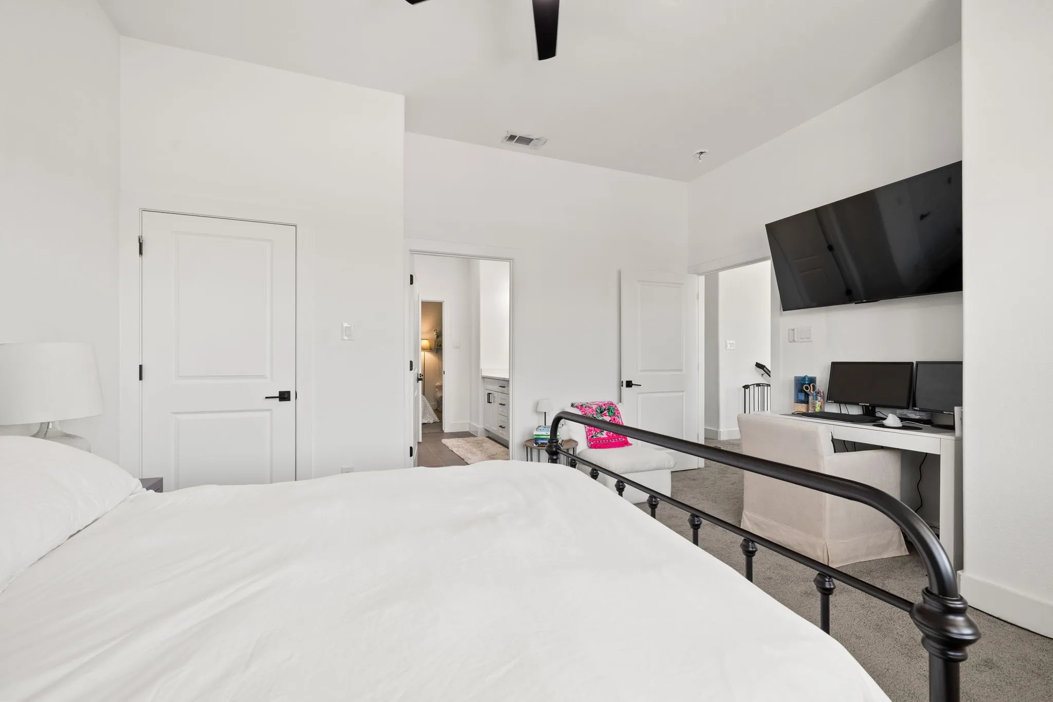 Spacious primary bedroom featuring clean white walls, recessed ceiling lighting, and a black metal bed frame