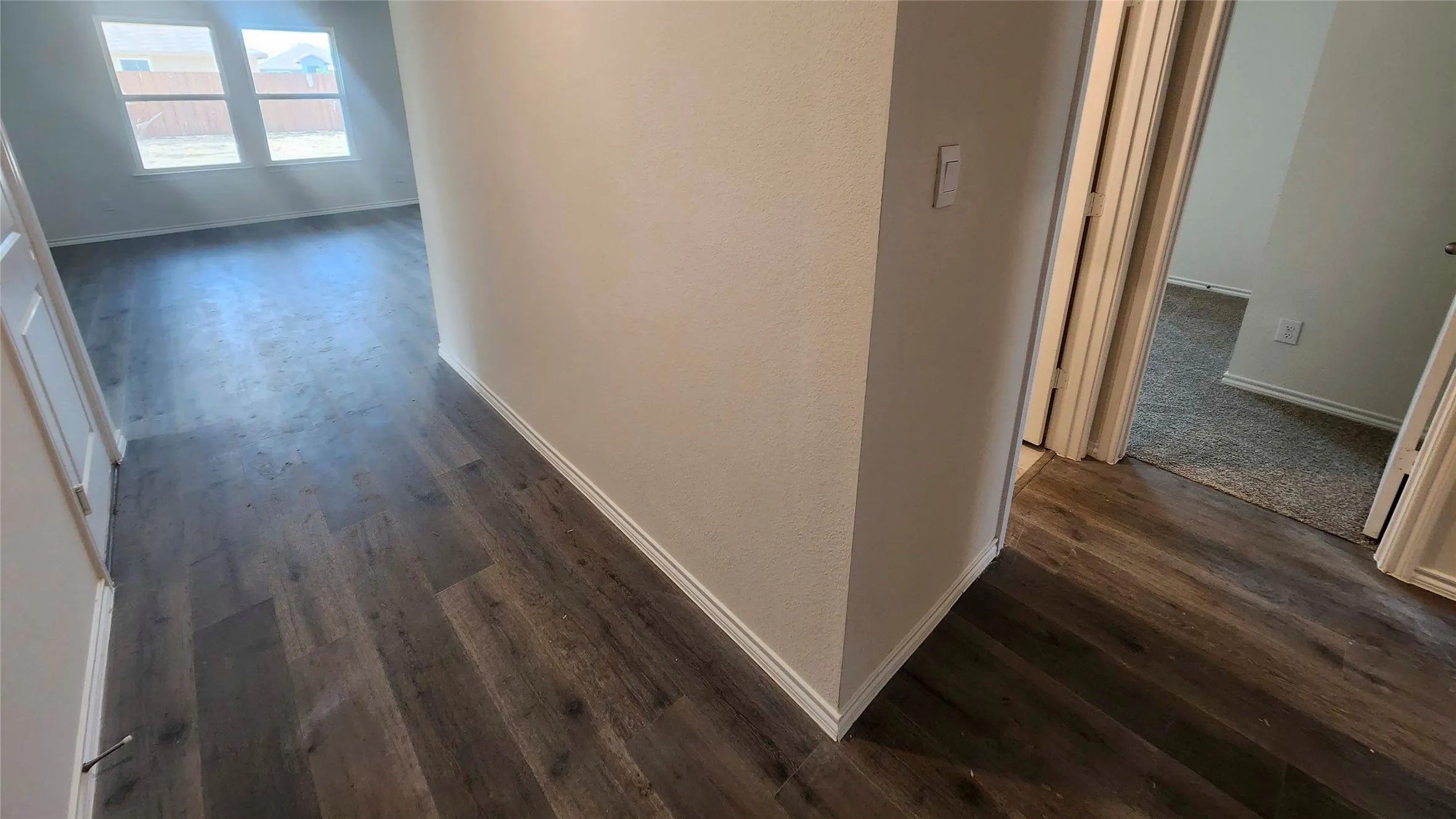 Modern hallway showcasing rich wood-finish flooring throughout, neutral wall finishes, and clean architectural lines