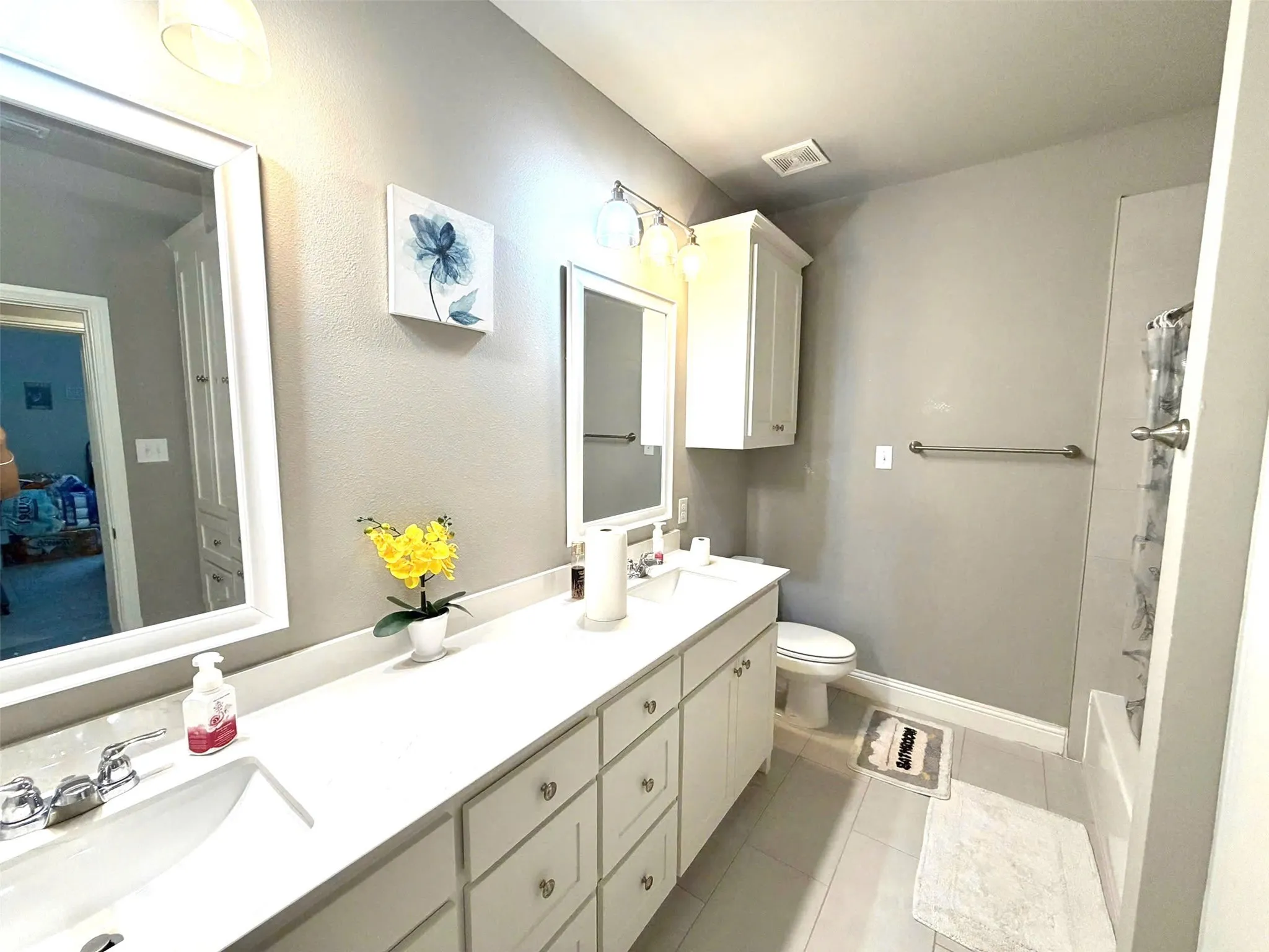 Bathroom featuring a spacious double vanity with white cabinetry, light countertops, and individual framed mirrors