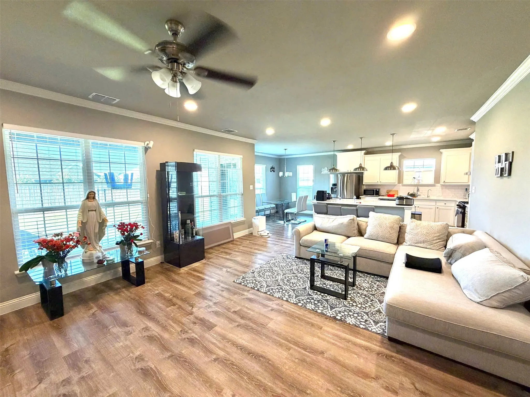 Open-concept living area featuring wood-finish flooring, recessed lighting, and crown molding