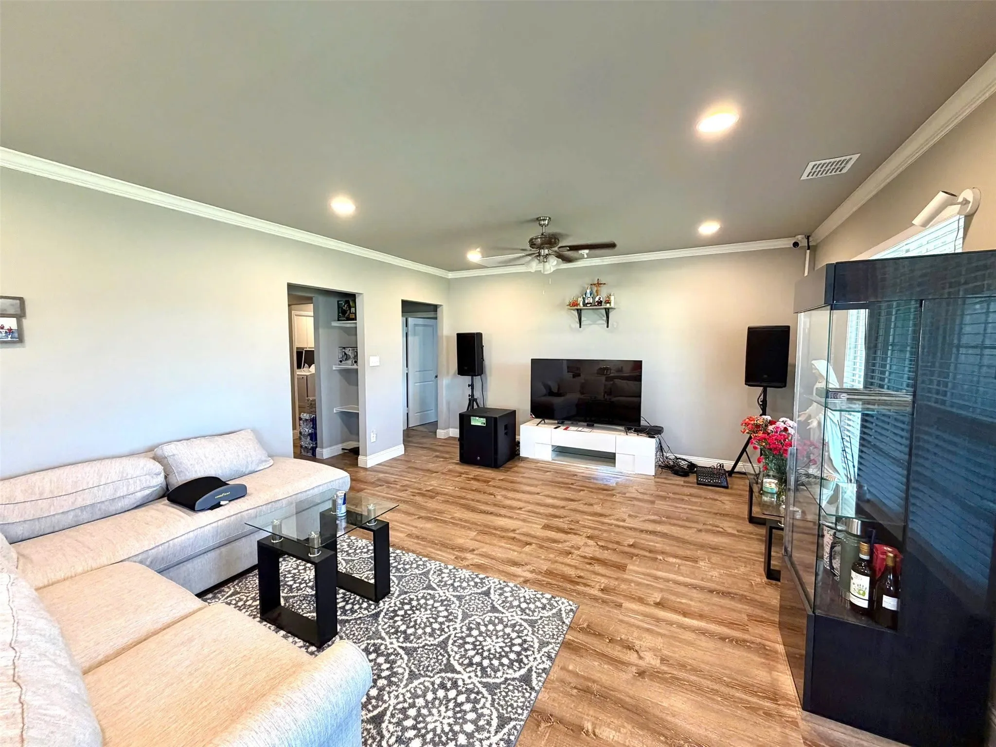 Spacious living room featuring wood-finish flooring, recessed ceiling lighting, and a ceiling fan