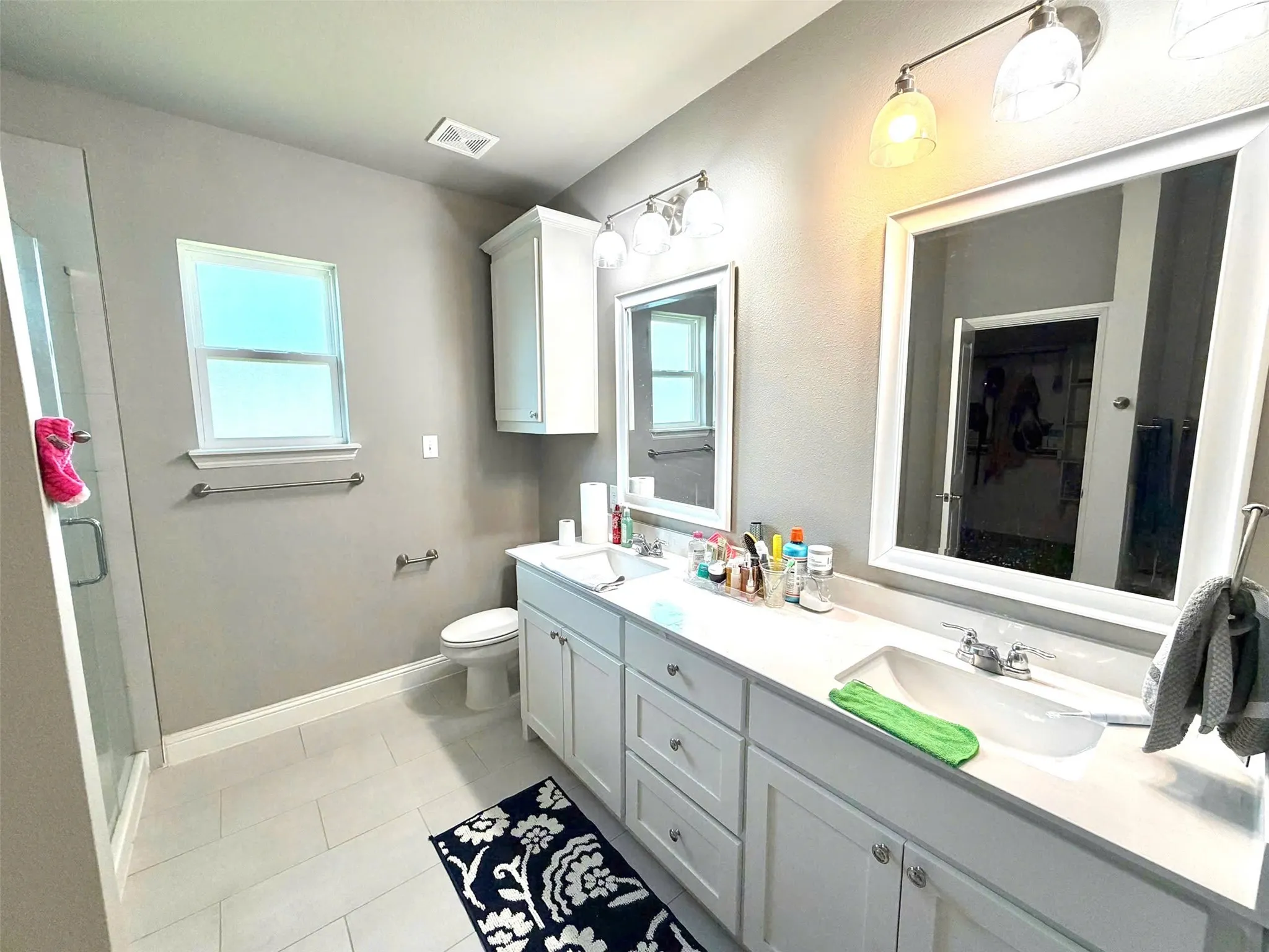 Double vanity with integrated sinks, white cabinetry, and wall-mounted mirrors
