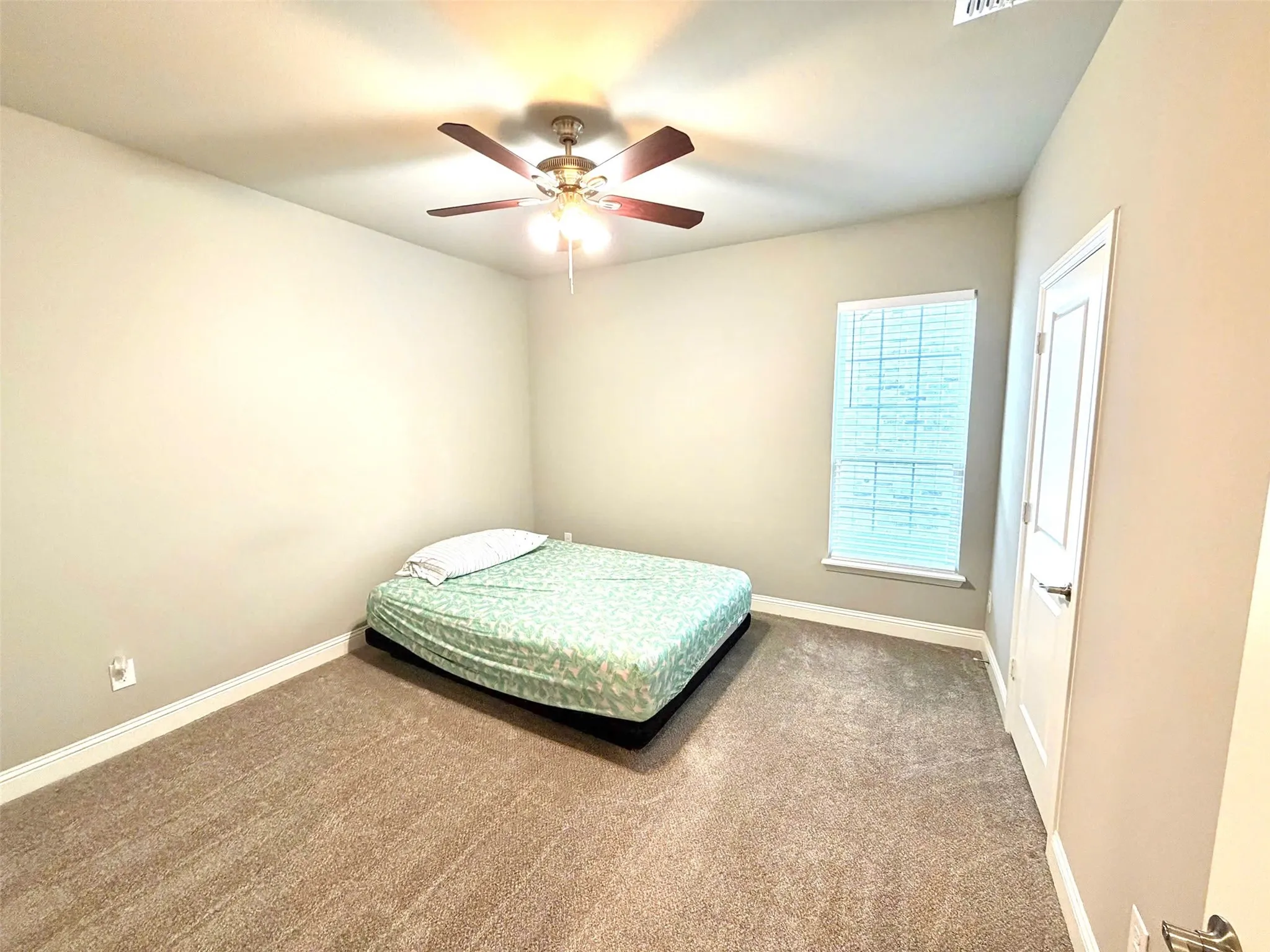 Carpeted room featuring a ceiling fan with integrated lighting, a window with horizontal blinds, a white door, and baseboard molding