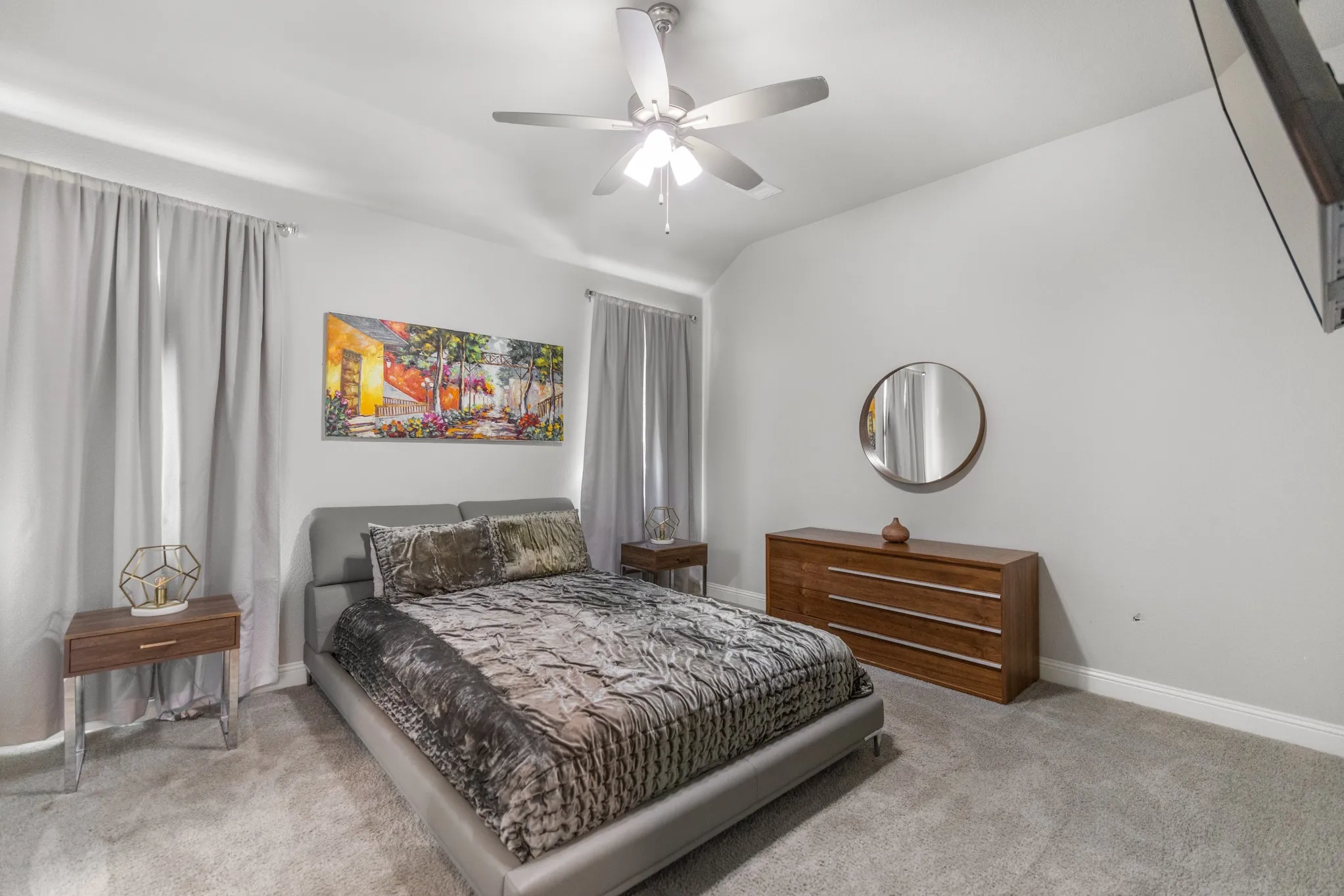 Spacious bedroom featuring a neutral color palette, carpet flooring, and ceiling fan with integrated lighting