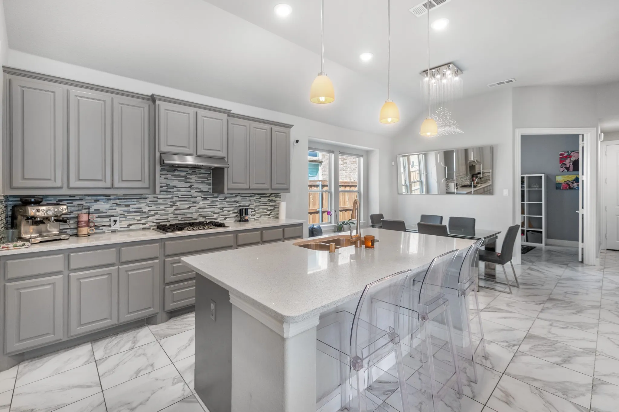 Stunning chef's kitchen featuring gray cabinetry with raised-panel doors, a linear tile backsplash, and stainless steel appliances