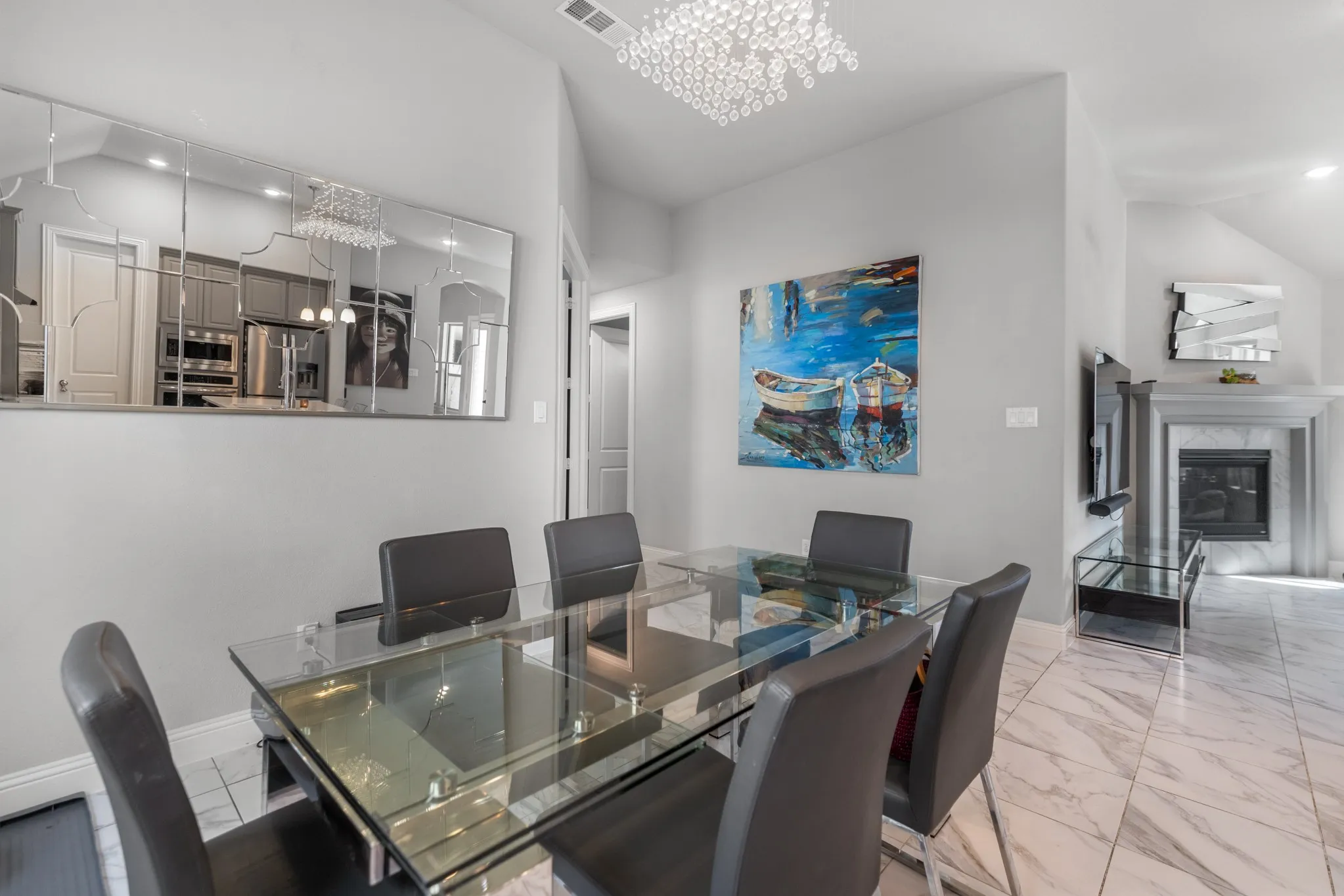 Dining area featuring a glass-top table, vaulted ceiling, and a prominent fireplace with a marble-look surround