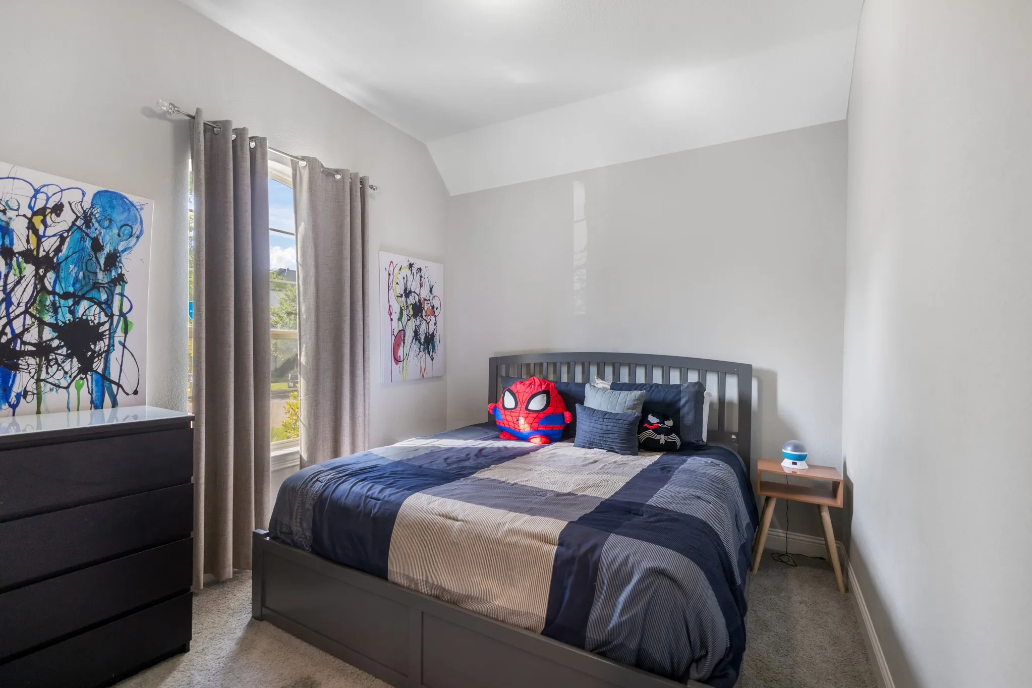 Bright bedroom featuring a dark wood-finish bed frame, soft carpet flooring, and large windows with thermal-lined curtains