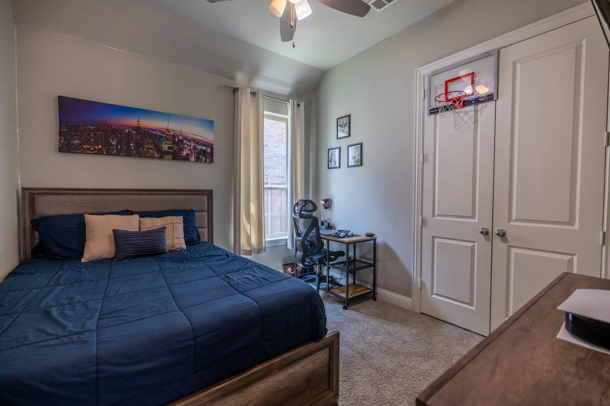 Bedroom featuring carpet flooring, a window with vertical blinds, a ceiling fan with integrated lighting, and a double-door closet