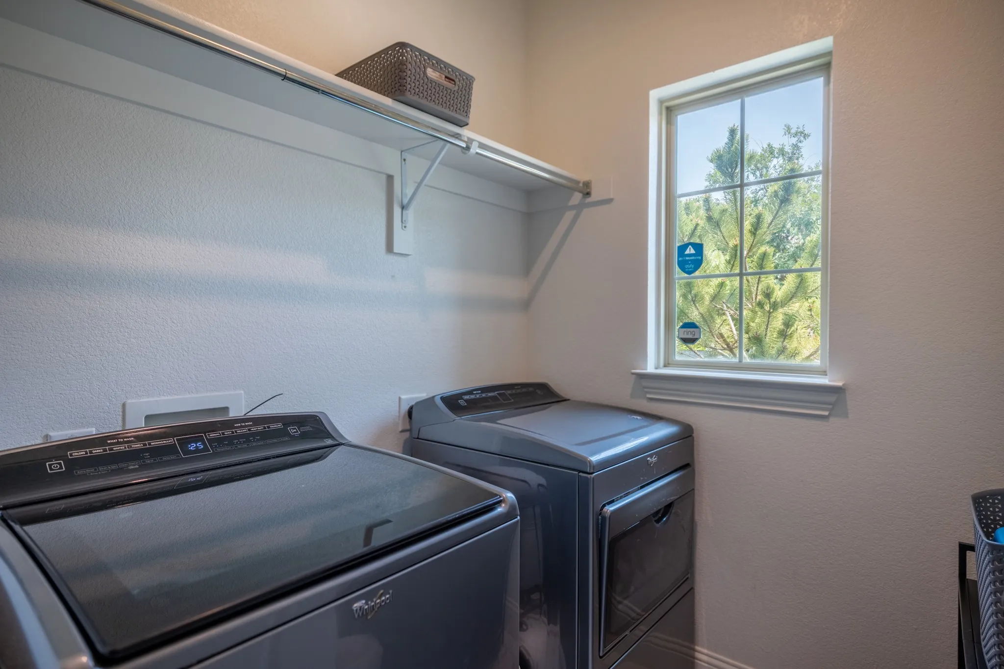 Laundry area featuring a large window, integrated shelving, and white textured walls