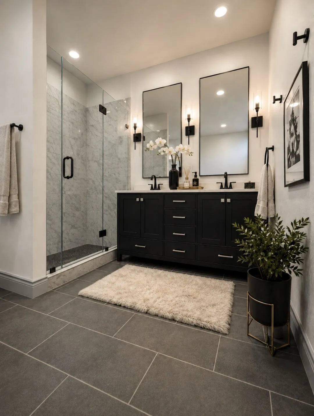 Bathroom featuring a dual vanity with dark cabinetry, dual rectangular mirrors, and wall-mounted sconce lighting