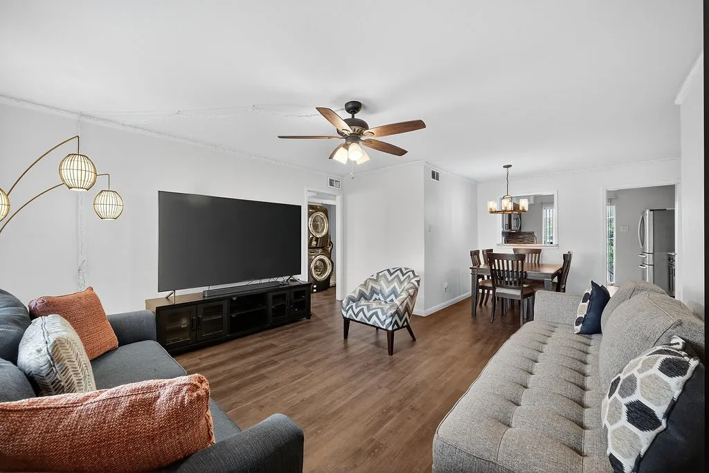 Open concept living area with wood-finish flooring, crown molding, and a ceiling fan