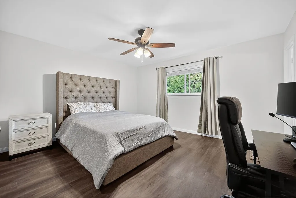 Spacious room featuring wood-finish flooring, a window with exterior views, and a ceiling fan with integrated lighting