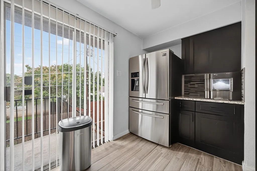 Stainless steel refrigerator and built-in microwave complement dark wood cabinetry and granite-look countertops