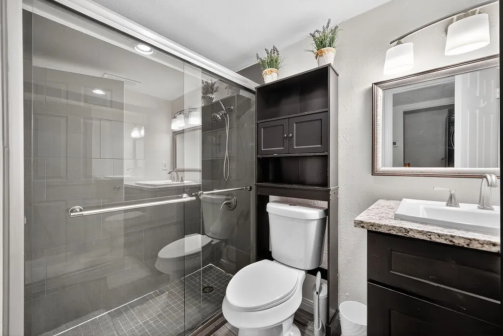 Full bathroom featuring a glass-enclosed shower with dark tile surround and a tiled floor