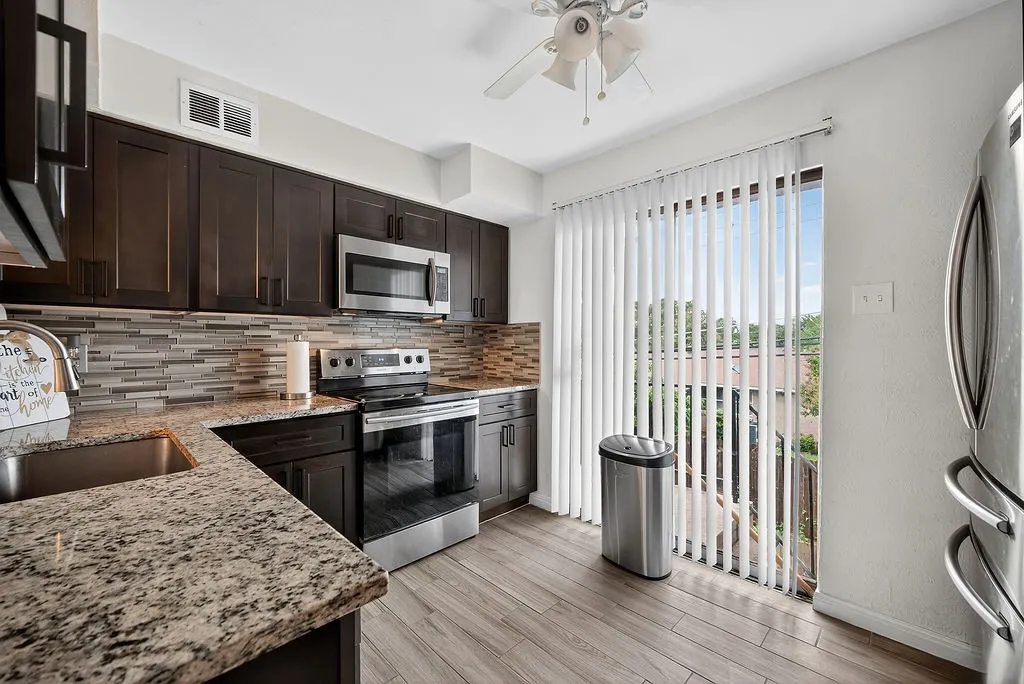 Kitchen featuring wood-finish flooring, dark wood cabinetry, and stone countertops