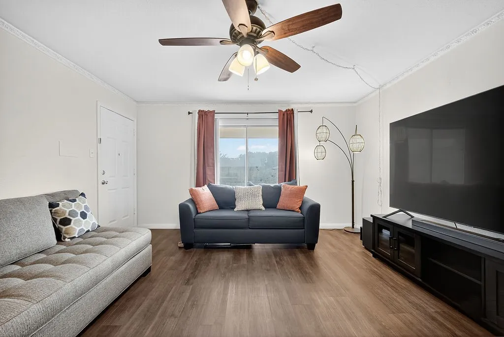 Living area featuring wood-finish flooring, white walls, and decorative crown molding