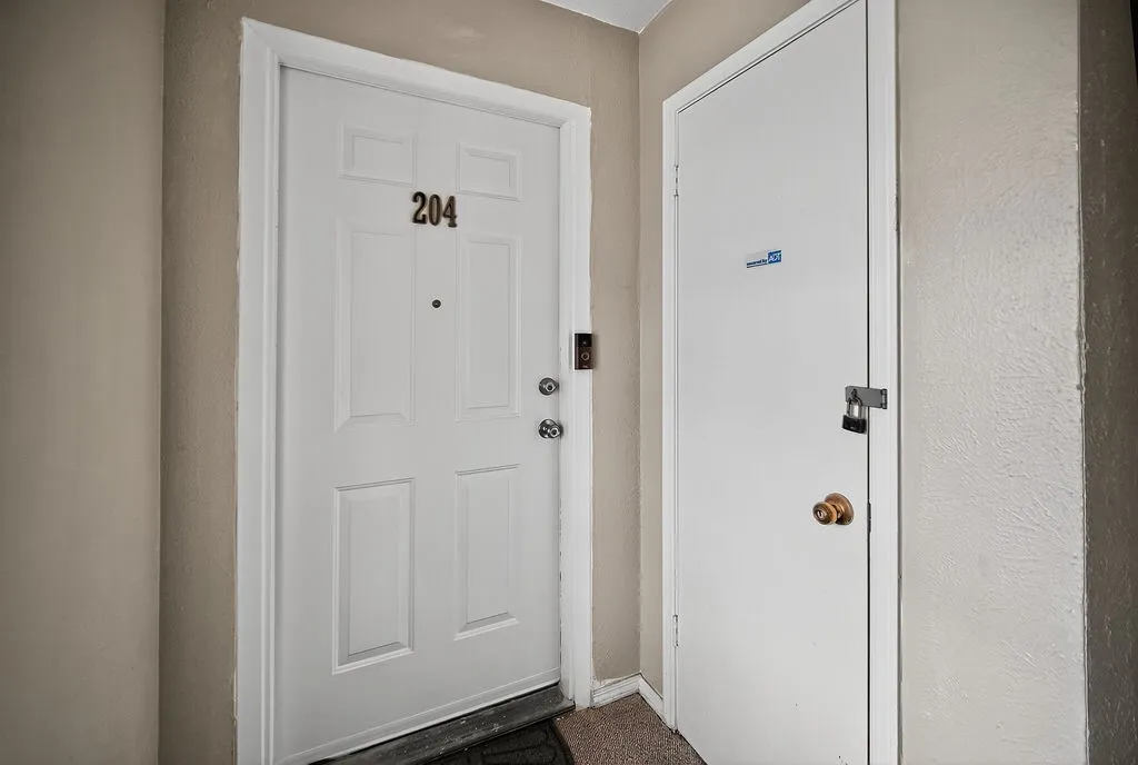 White four-panel door with brass hardware and visible unit number