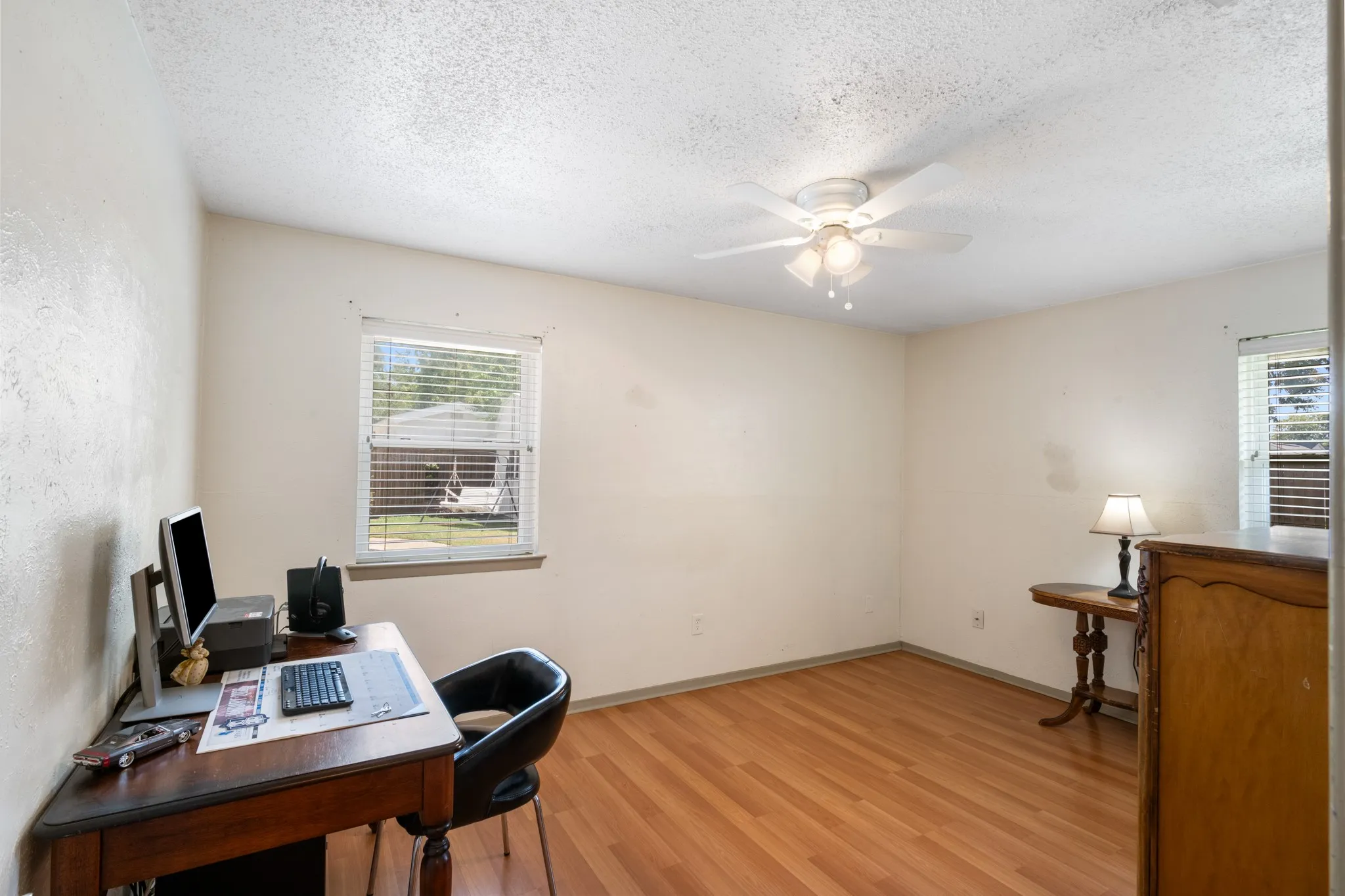 Room featuring wood-finish flooring, a window with horizontal blinds, and a ceiling fan with integrated lighting