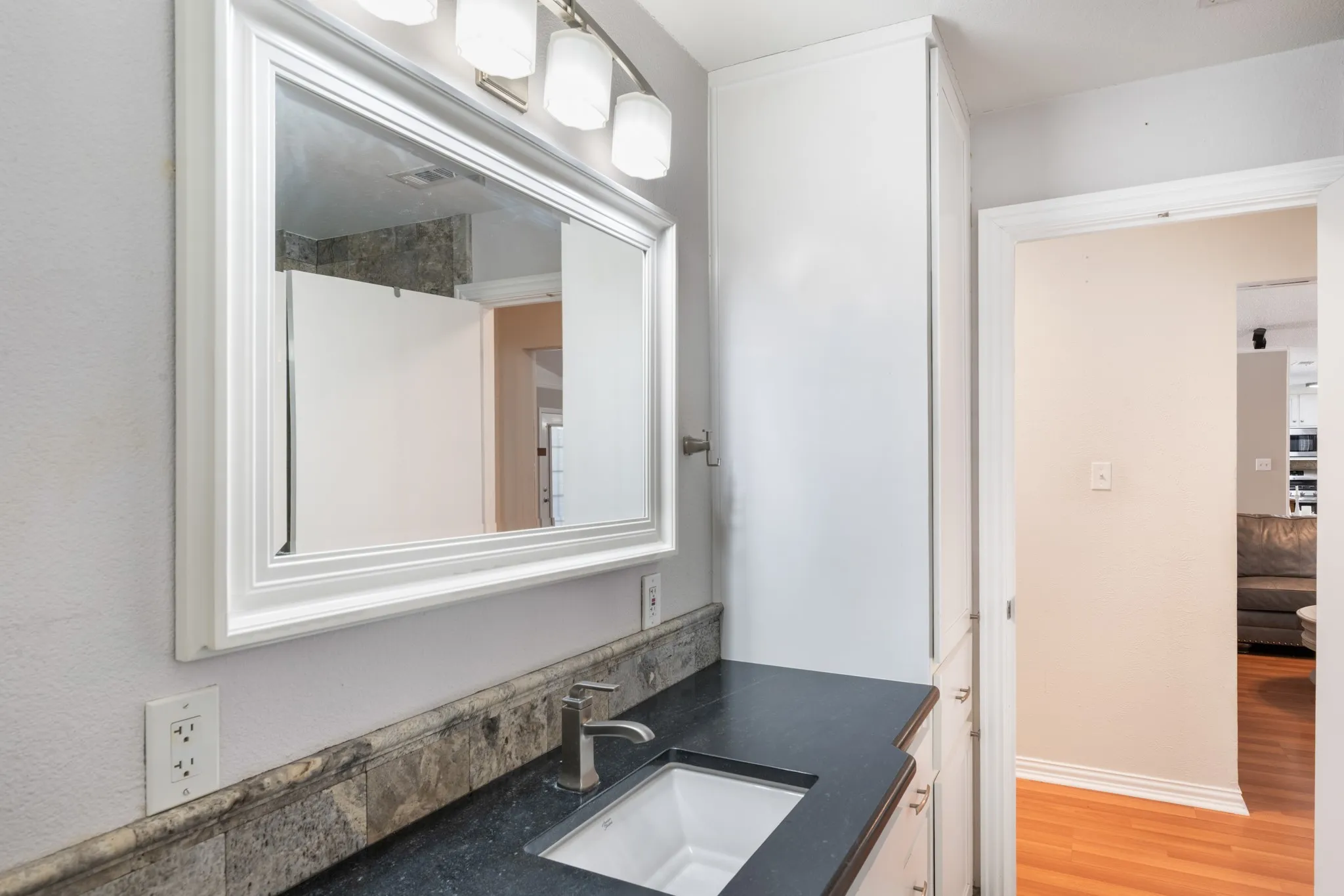 Bright ensuite bathroom featuring a framed mirror with integrated lighting above a dual-sink vanity