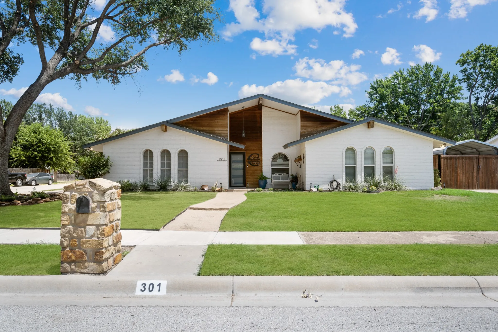 Modern architectural home featuring a striking pitched roof with wood-beam detailing and cream-finished exterior walls