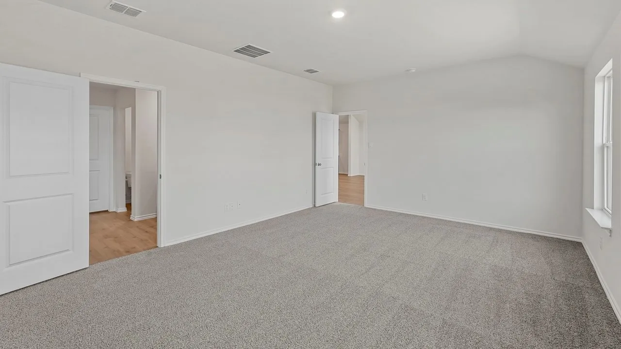 Spacious room featuring vaulted ceilings, a large window with white trim, and light grey carpeting