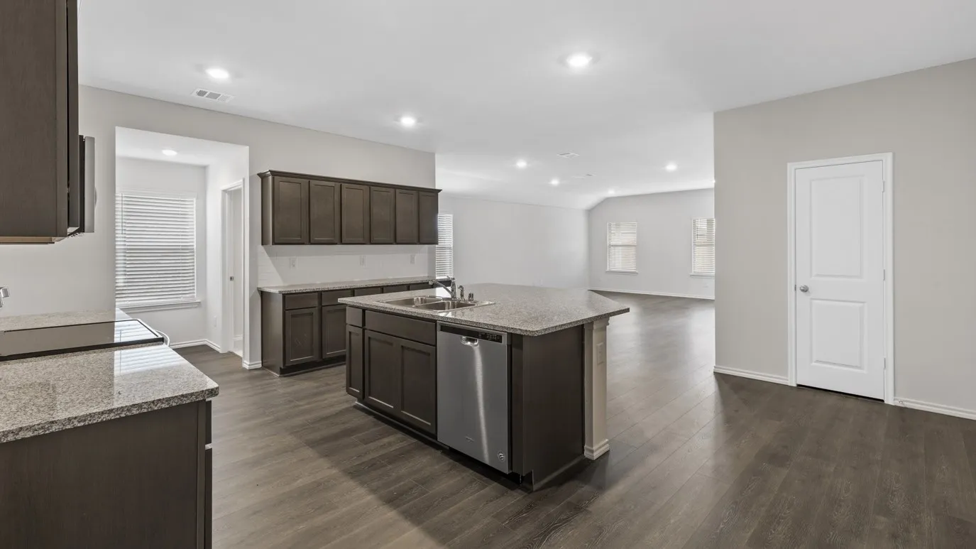 Spacious kitchen featuring dark wood cabinetry, granite countertops, a central island with a stainless steel dishwasher, and recessed lighting