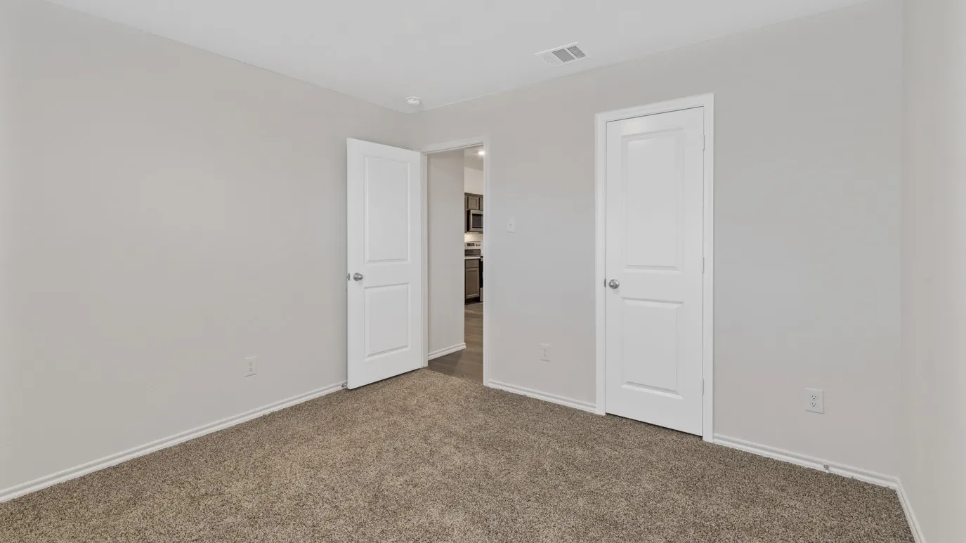 Carpeted room featuring light gray walls, white baseboards, and two white paneled doors