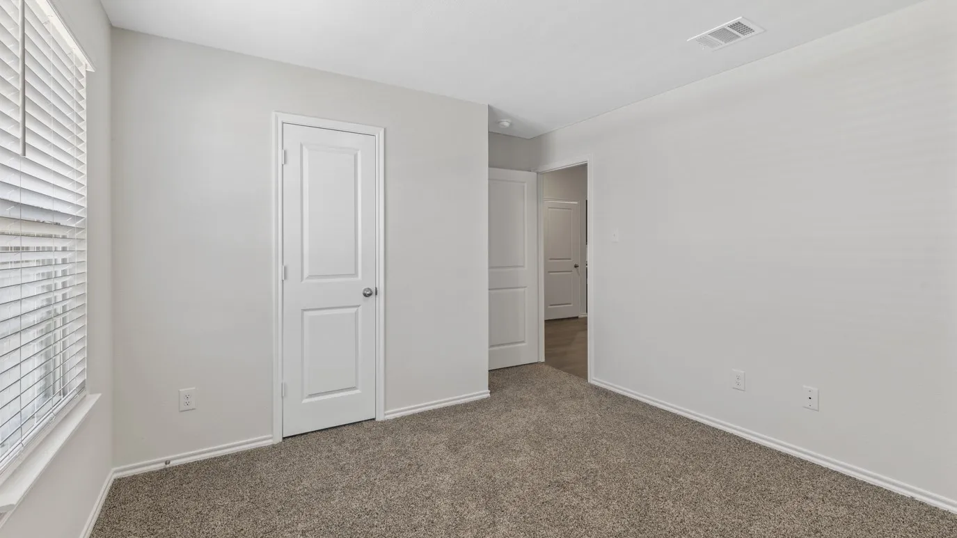 Carpeted room featuring a window with horizontal blinds, white baseboards, and two paneled interior doors