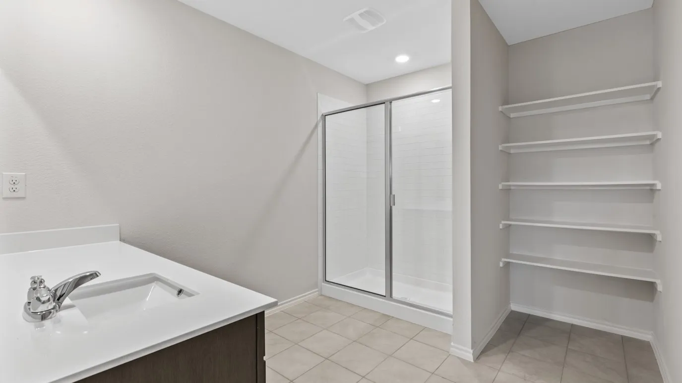 Bathroom featuring a single vanity with an integrated sink, a glass-enclosed shower, and built-in shelving