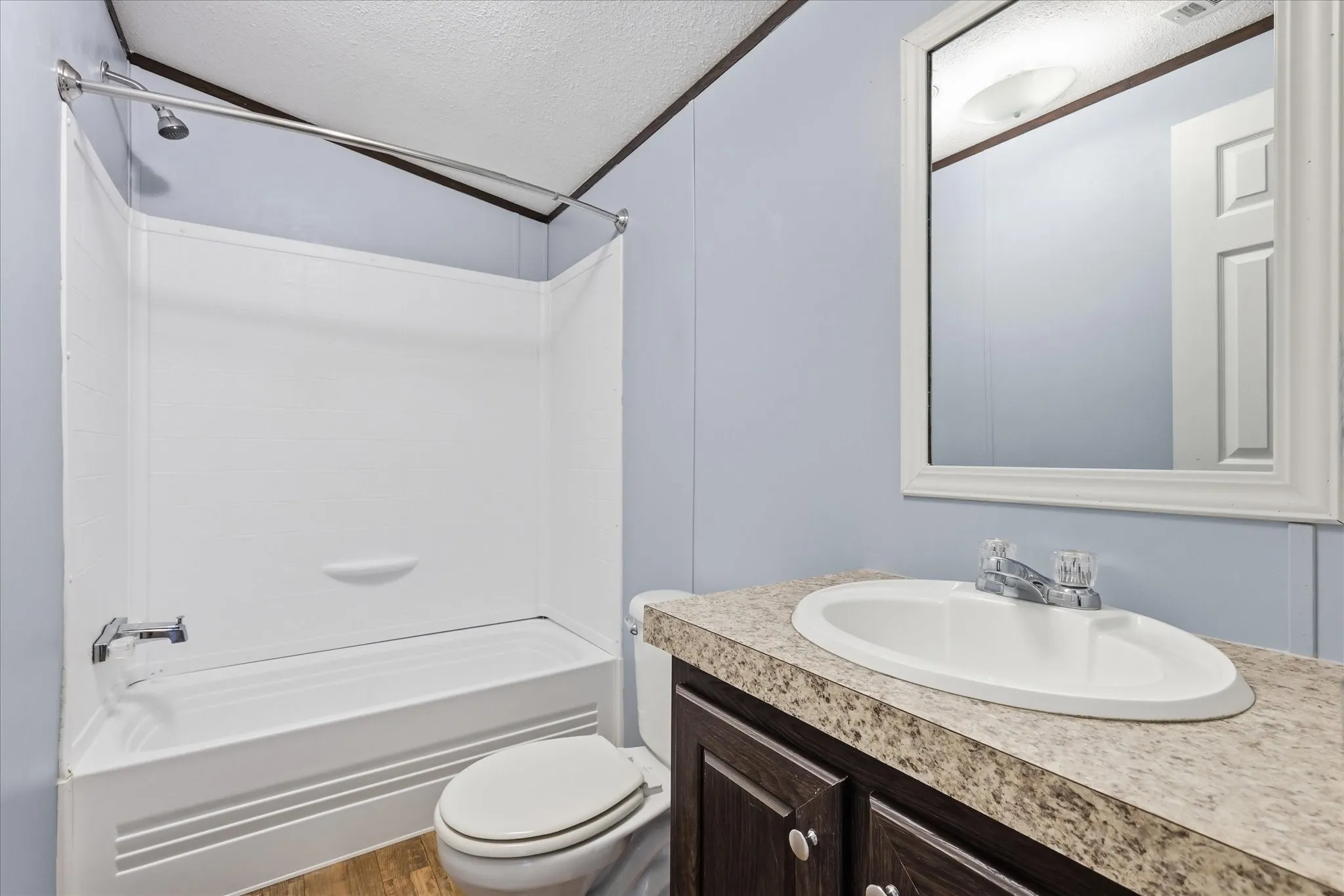 Spa-inspired bathroom featuring a granite-topped vanity with an oval porcelain sink and chrome faucet, paired with a white ceramic toilet and alcove bathtub/shower combination