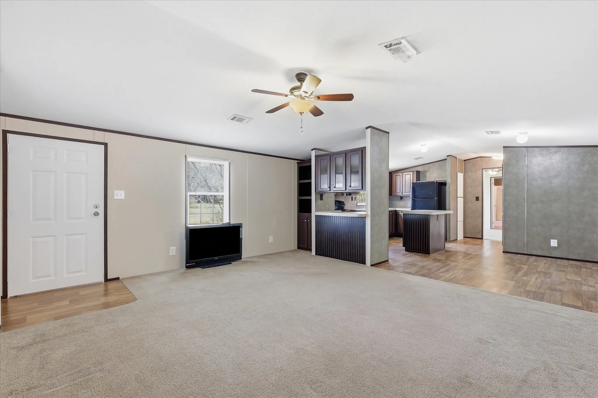 Spacious open-concept living area featuring wood-finish flooring, neutral wall finishes, and abundant natural light