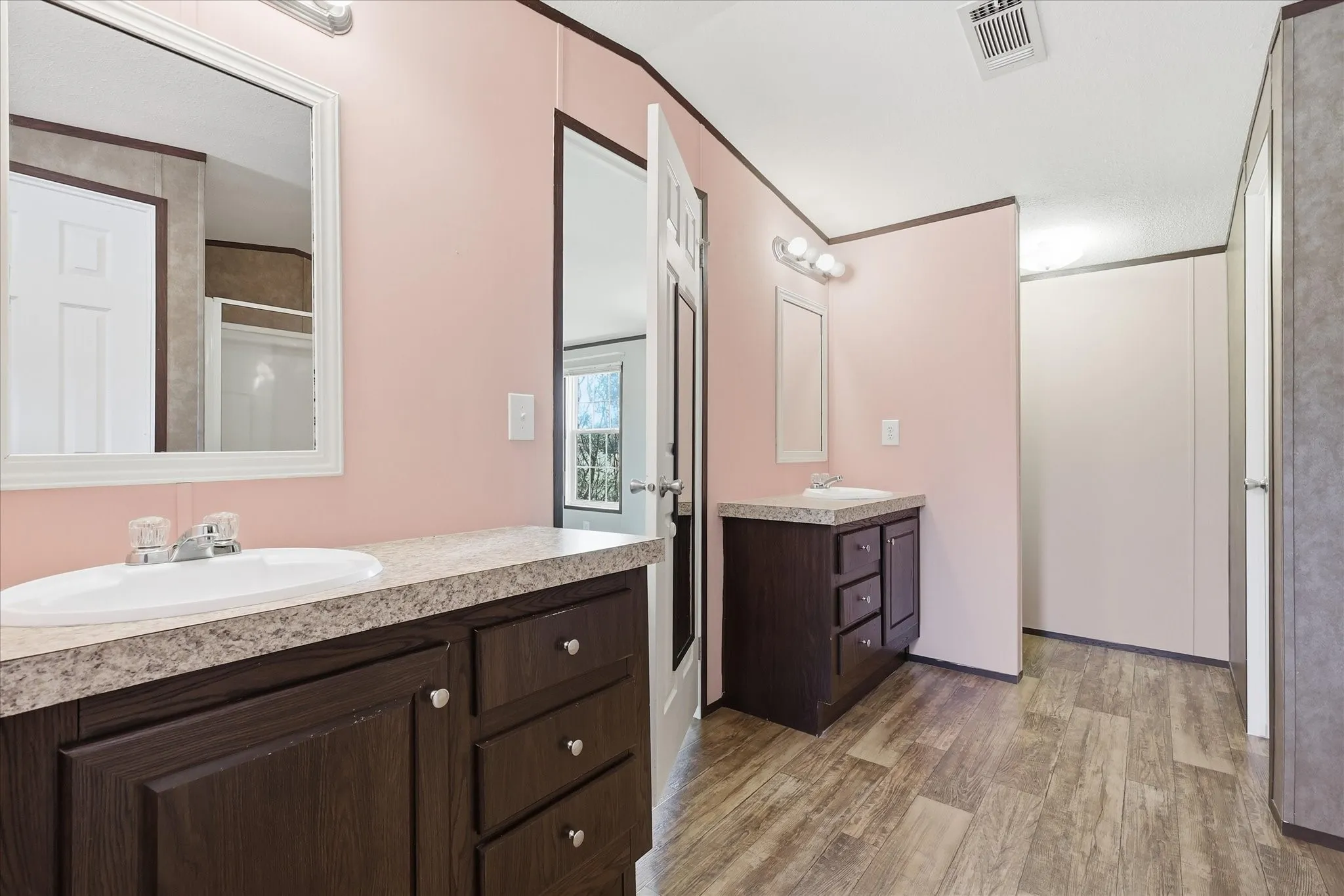 Bathroom featuring dual vanity areas with laminate countertops and wood-finish cabinetry