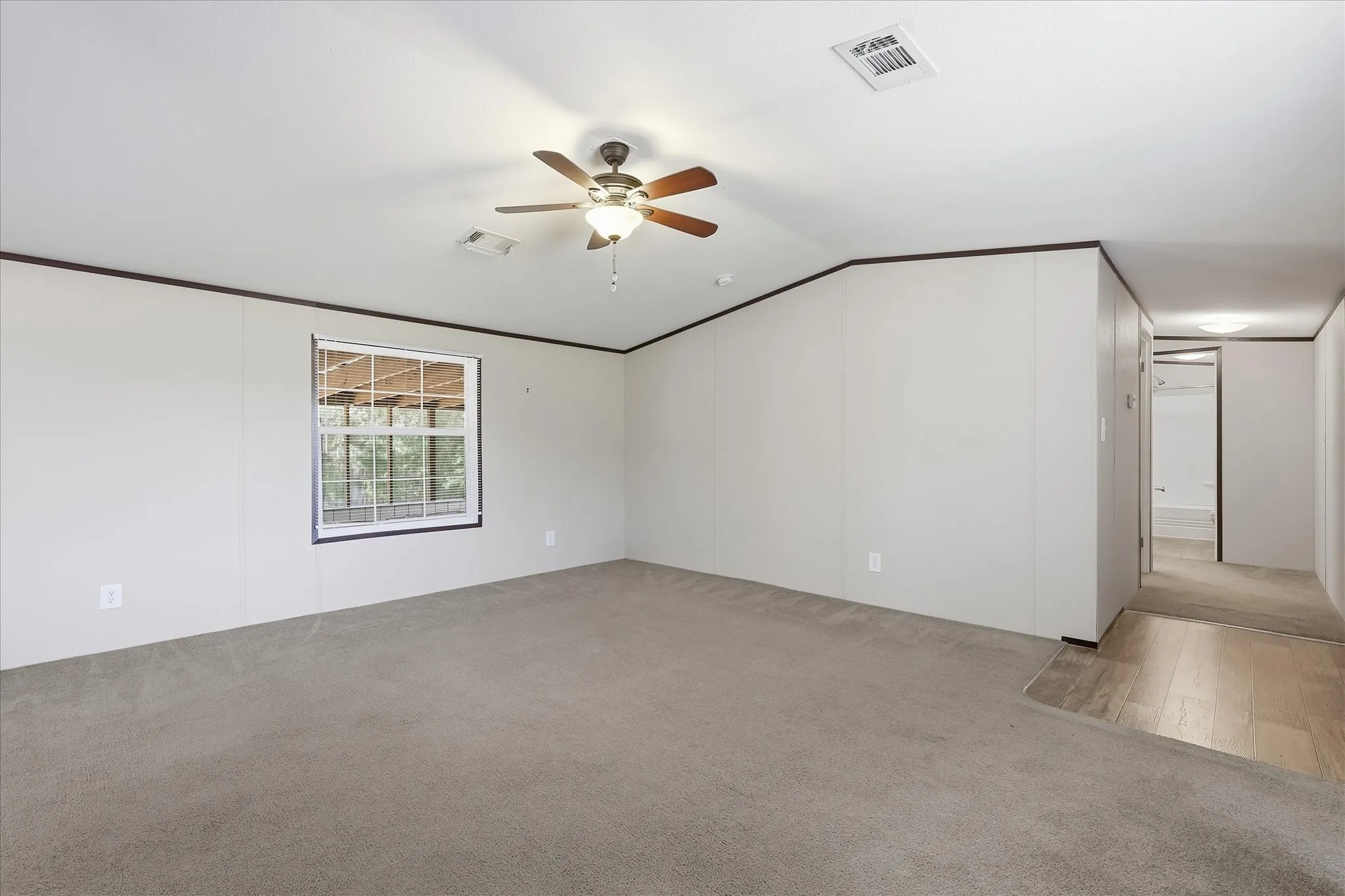 Spacious room with light-colored walls and dark trim, featuring a ceiling fan with integrated lighting