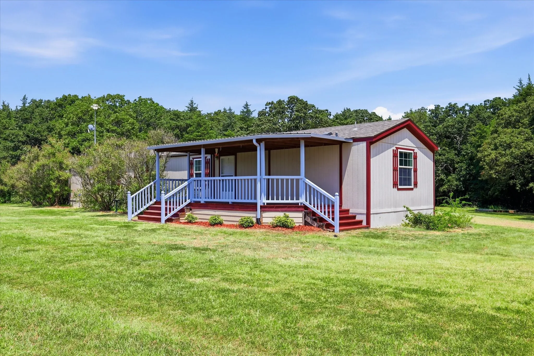 Exterior featuring a covered porch with white railings, red steps, and a matching red-trimmed window with shutters
