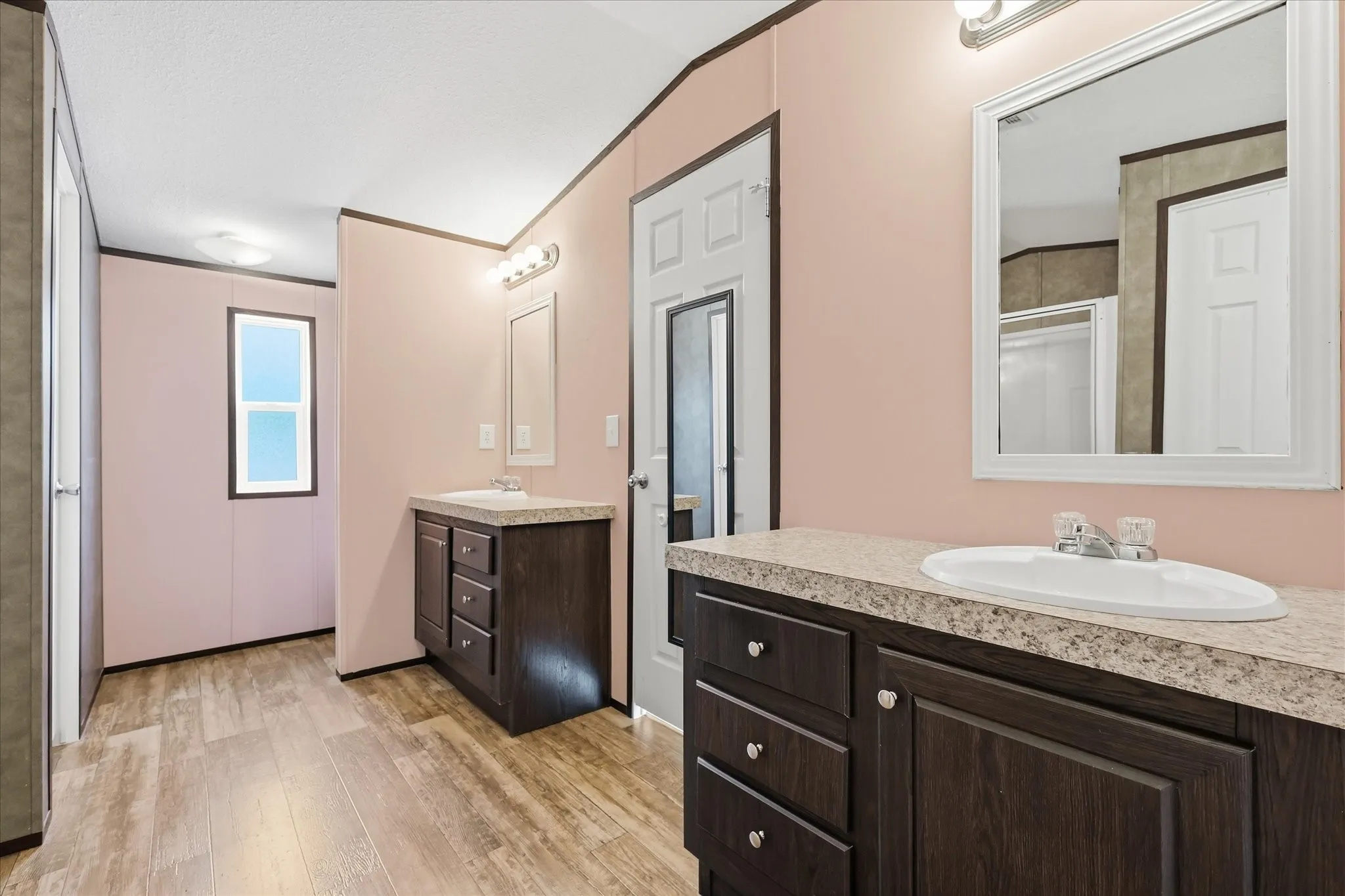 Spa-inspired primary bathroom featuring dual vanities with dark cabinetry, granite countertops, and vessel sink