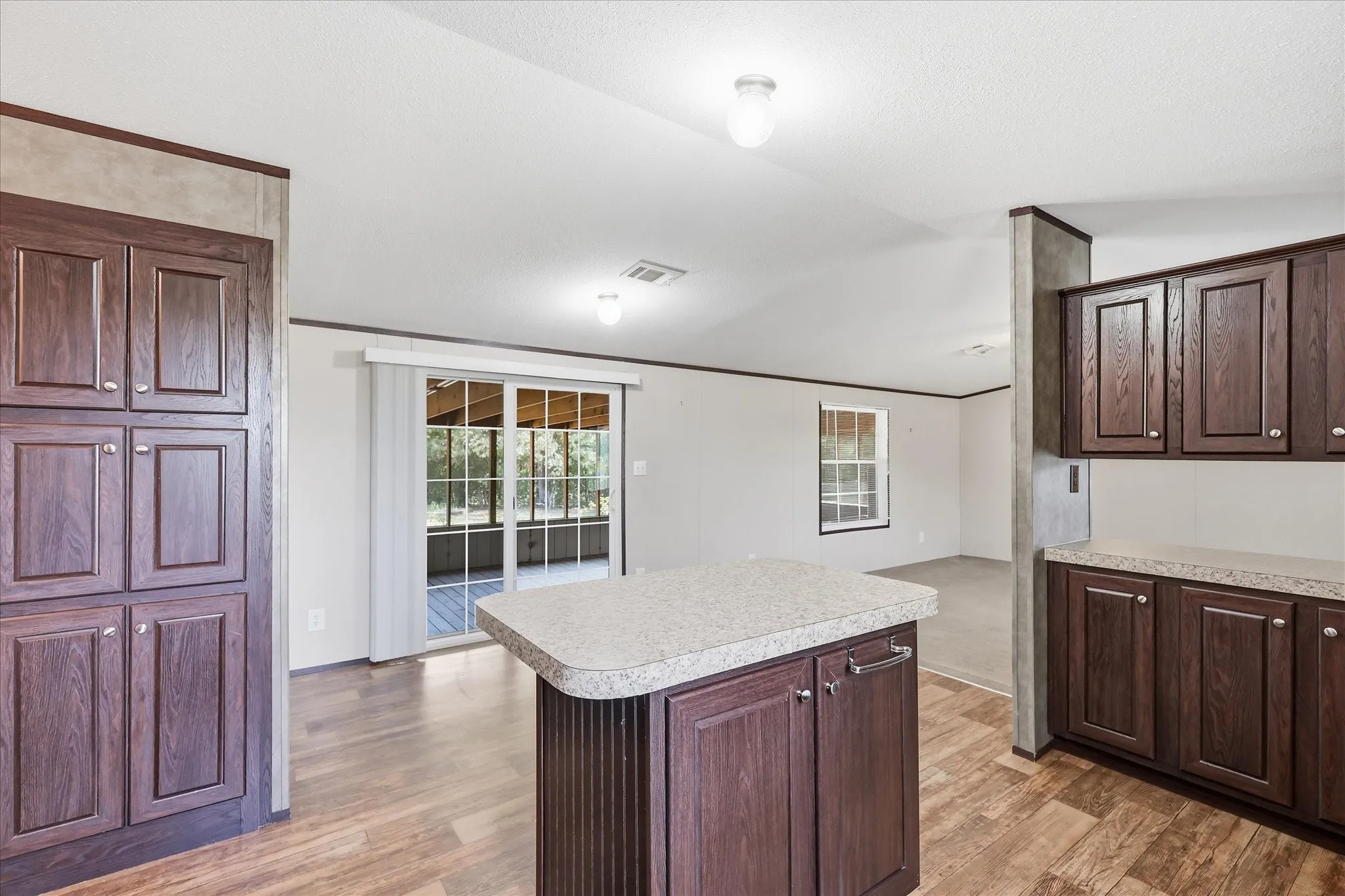 Spacious kitchen featuring a large island with white quartz countertop, rich wood-finish cabinetry, recessed lighting, and hardwood flooring