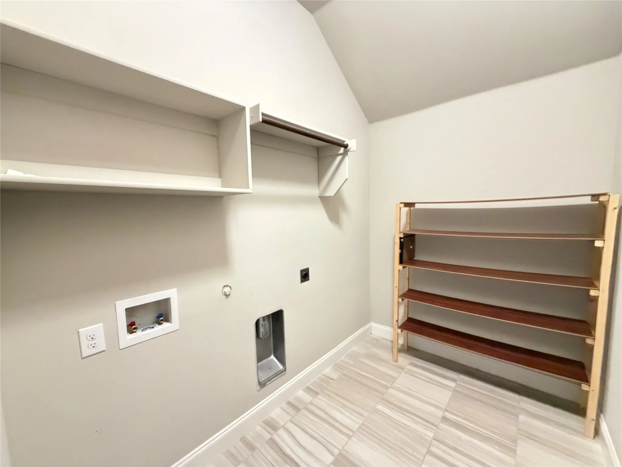 Laundry area featuring light-toned wall paint and light-colored tile flooring