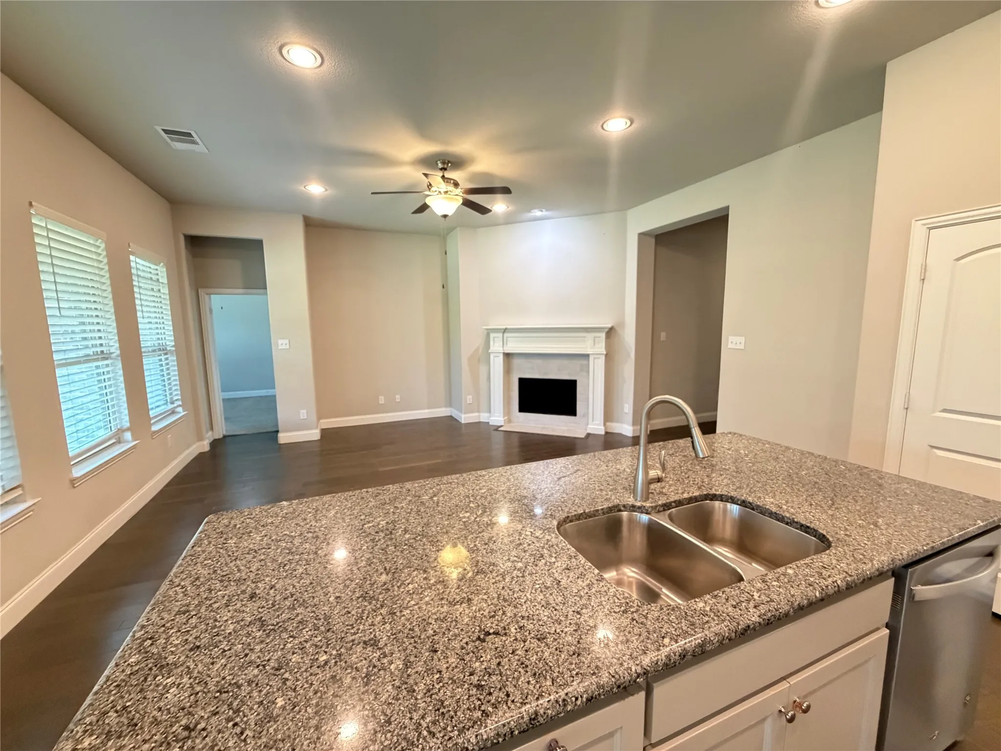 Kitchen island featuring a dual basin sink with a gooseneck faucet, light-toned cabinetry, and a built-in dishwasher
