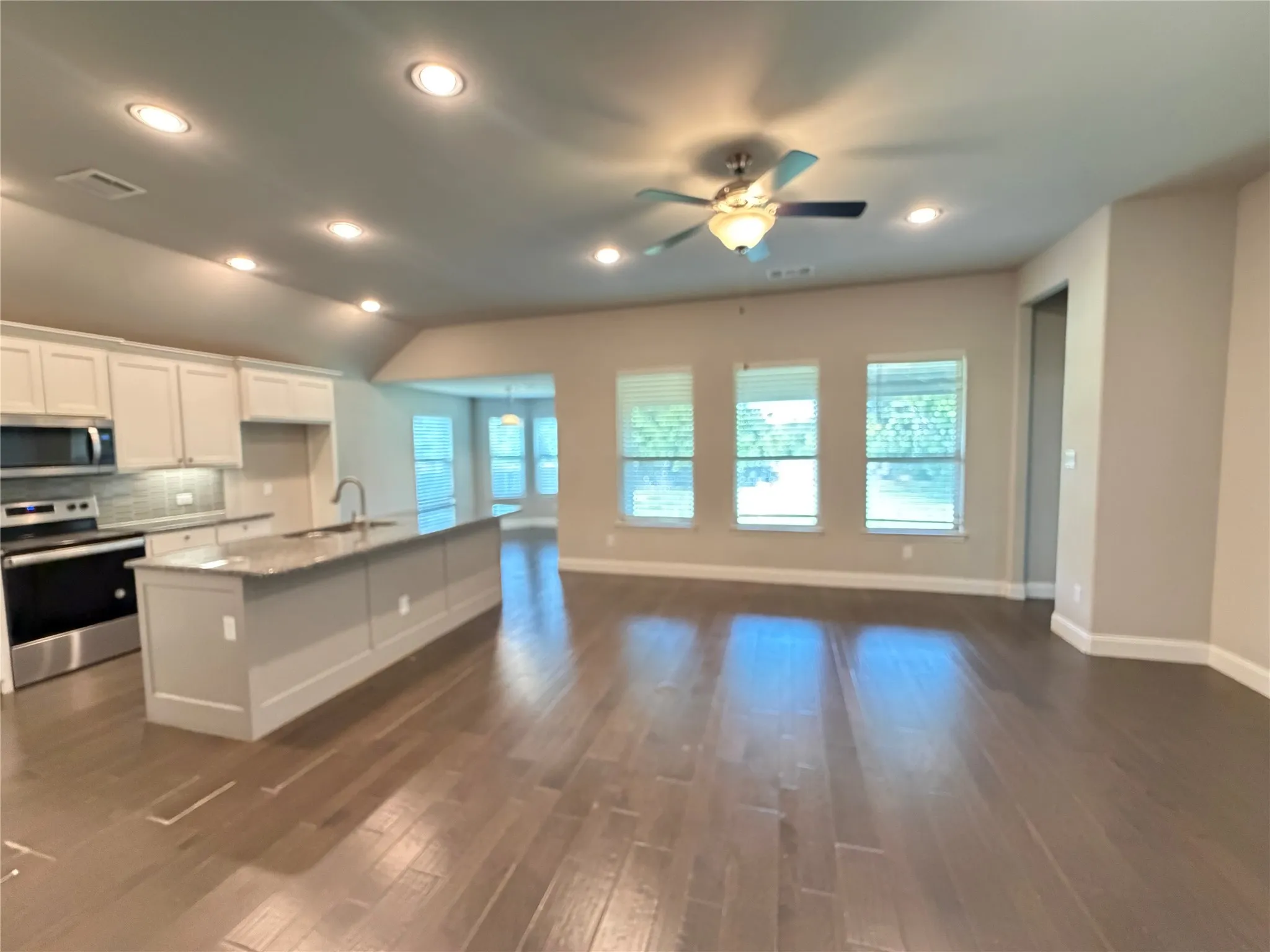 Open-concept living space featuring wood-finish flooring, recessed lighting, and a ceiling fan