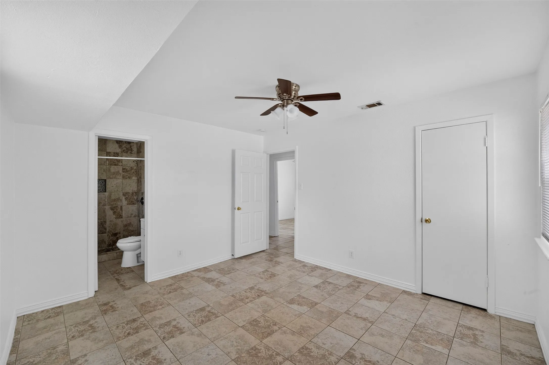 Spacious room featuring neutral-toned square tile flooring and white walls