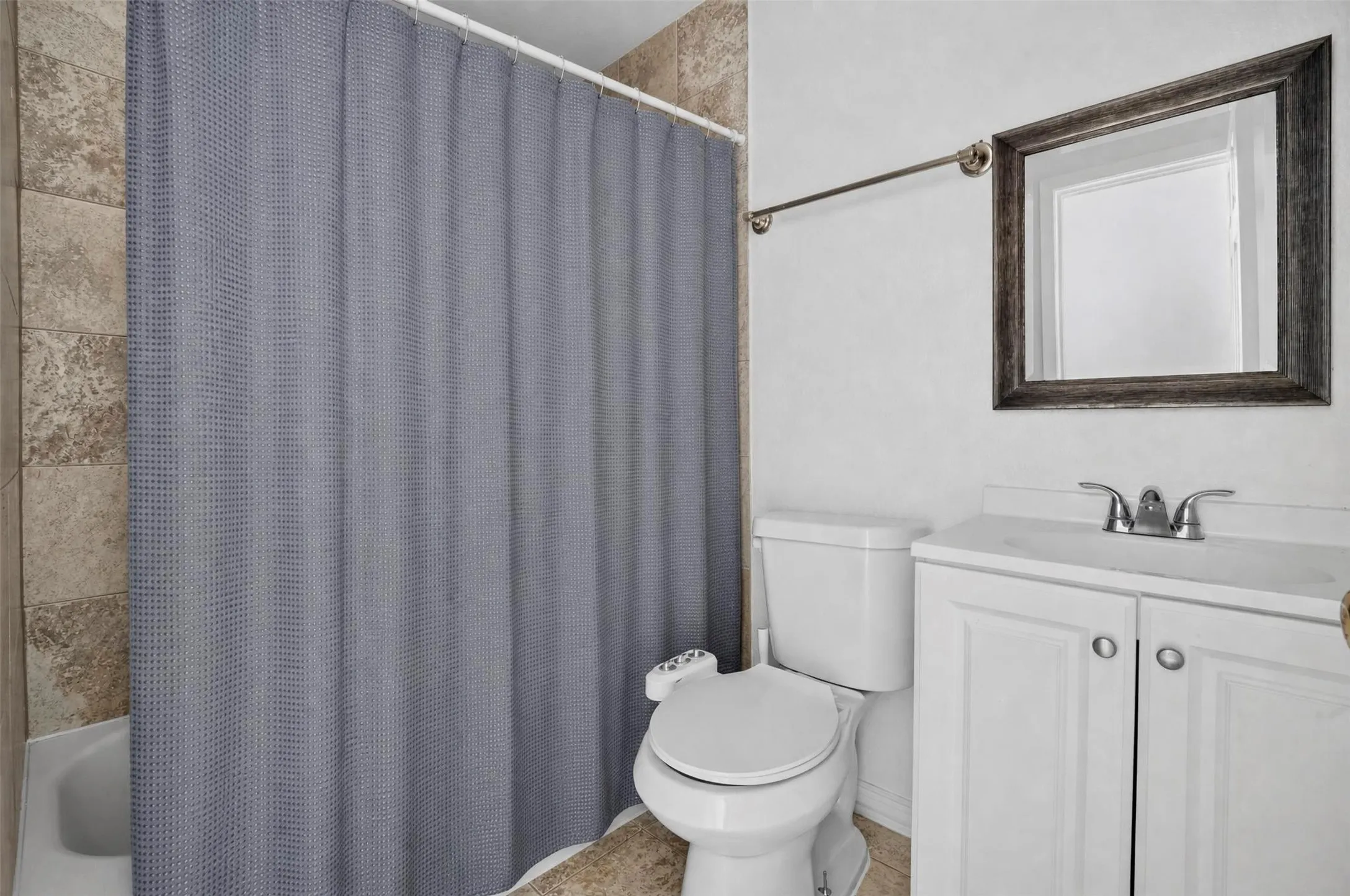 Bathroom featuring a white vanity with cabinet storage, a white sink, and a framed wall mirror